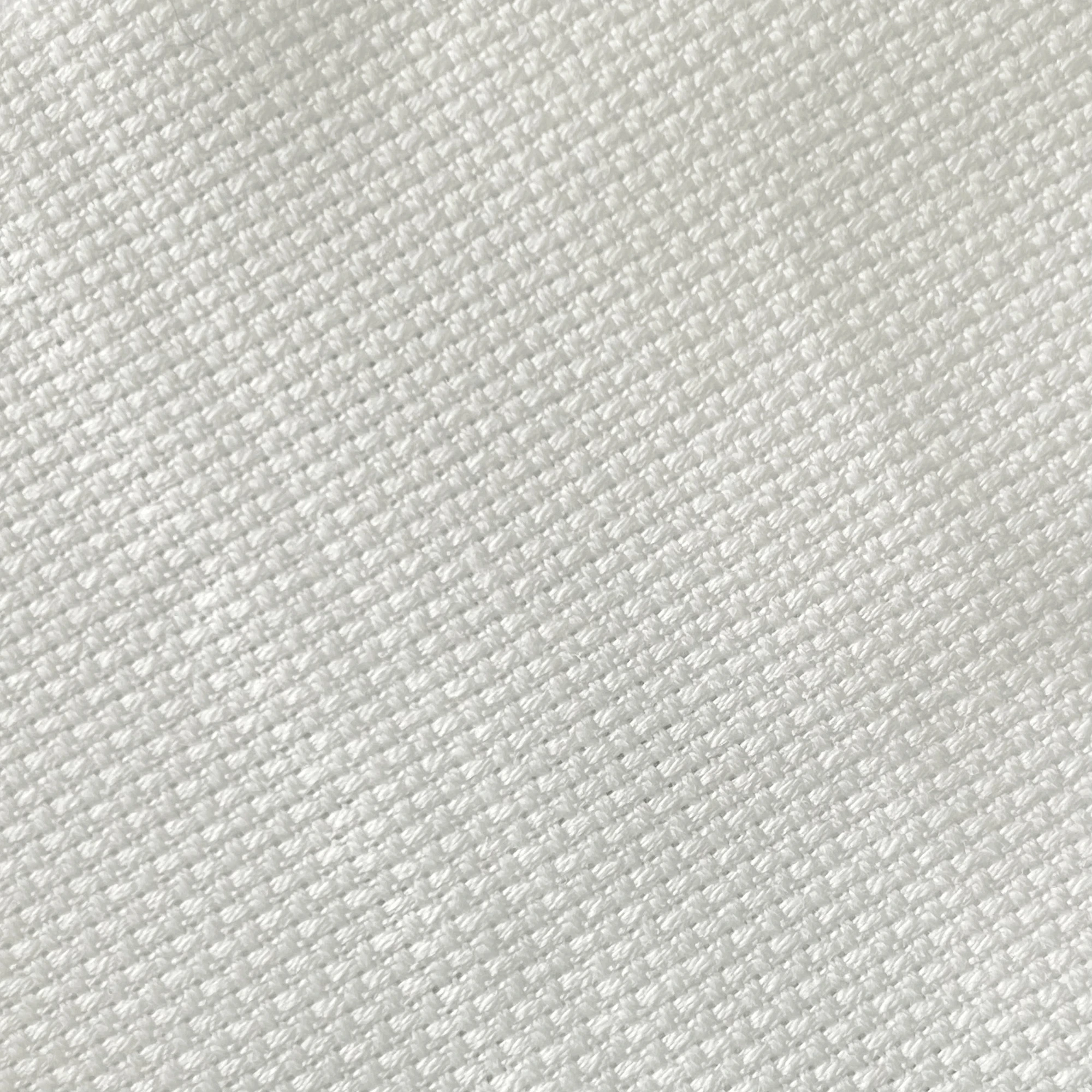 Close-up of white woven fabric texture, showcasing its detailed pattern and soft appearance.
