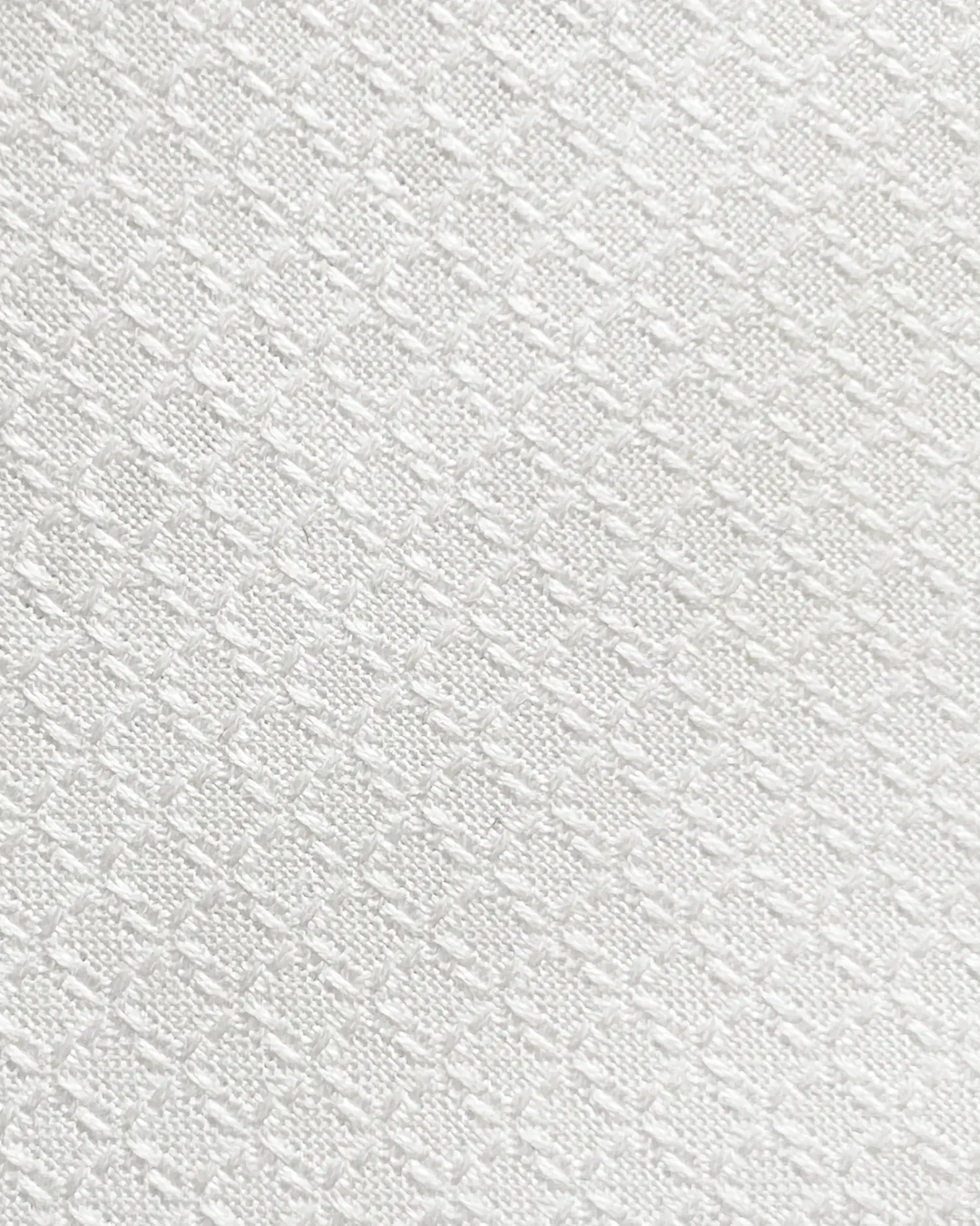 Close-up of white textured fabric with a diamond pattern design, ideal for textiles and interior design.