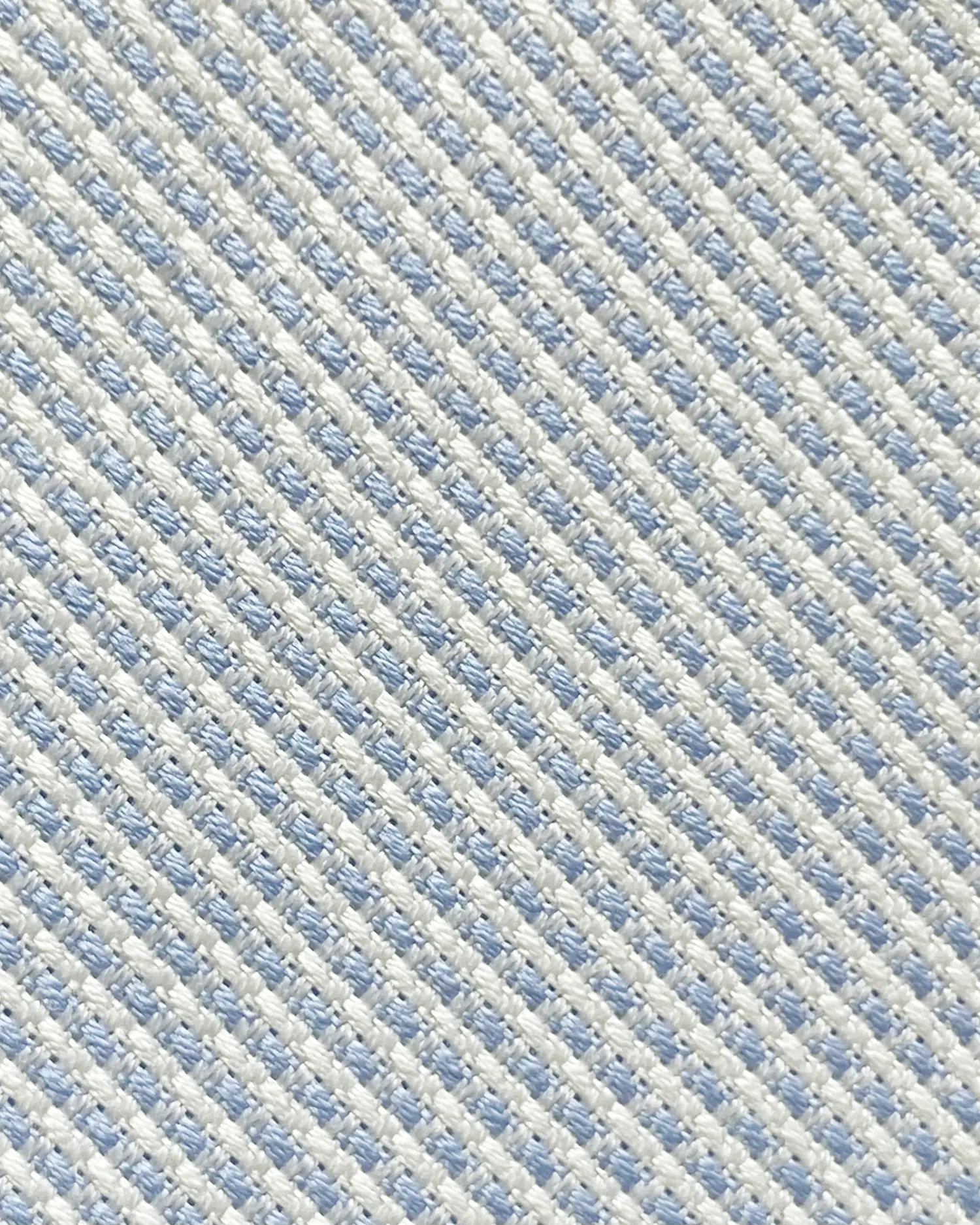 Close-up of light blue and white woven fabric, showcasing the intricate textured pattern in diagonal alignment.