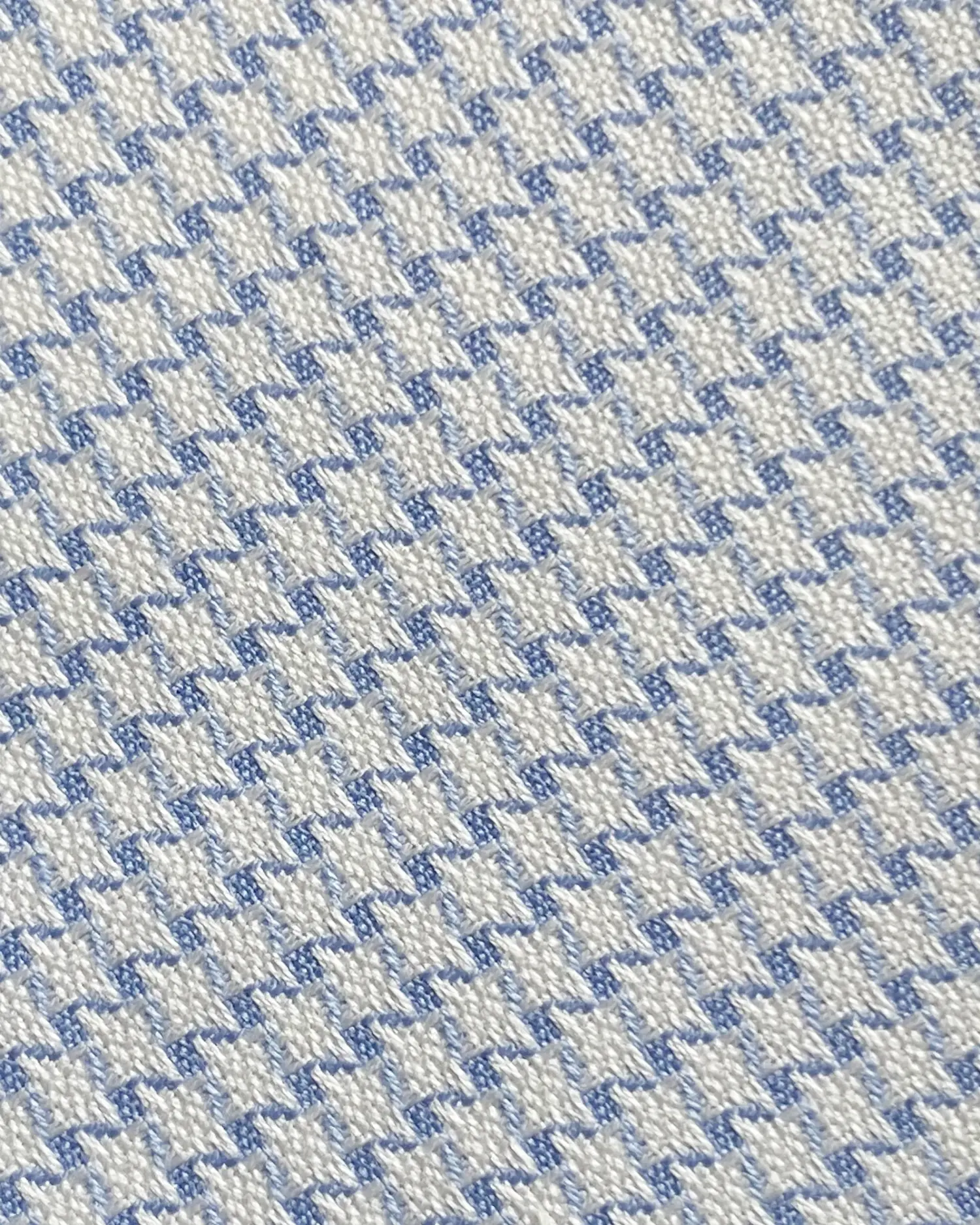 Close-up of blue and white houndstooth fabric pattern, showcasing intricate textile weave detail.
