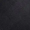 Close-up of a black herringbone fabric texture with diagonal zigzag pattern, ideal for fashion and interior design projects.