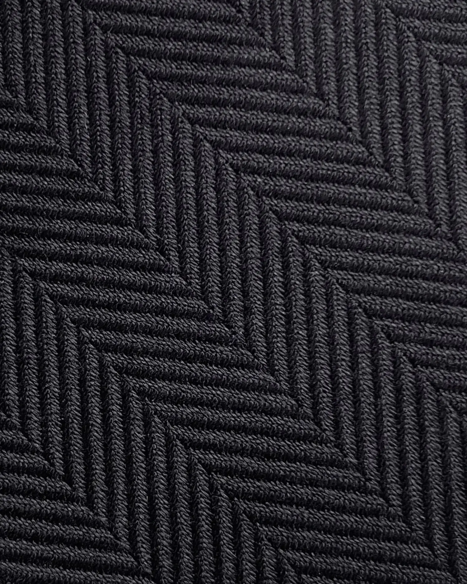 Close-up of a black herringbone fabric texture with diagonal zigzag pattern, ideal for fashion and interior design projects.