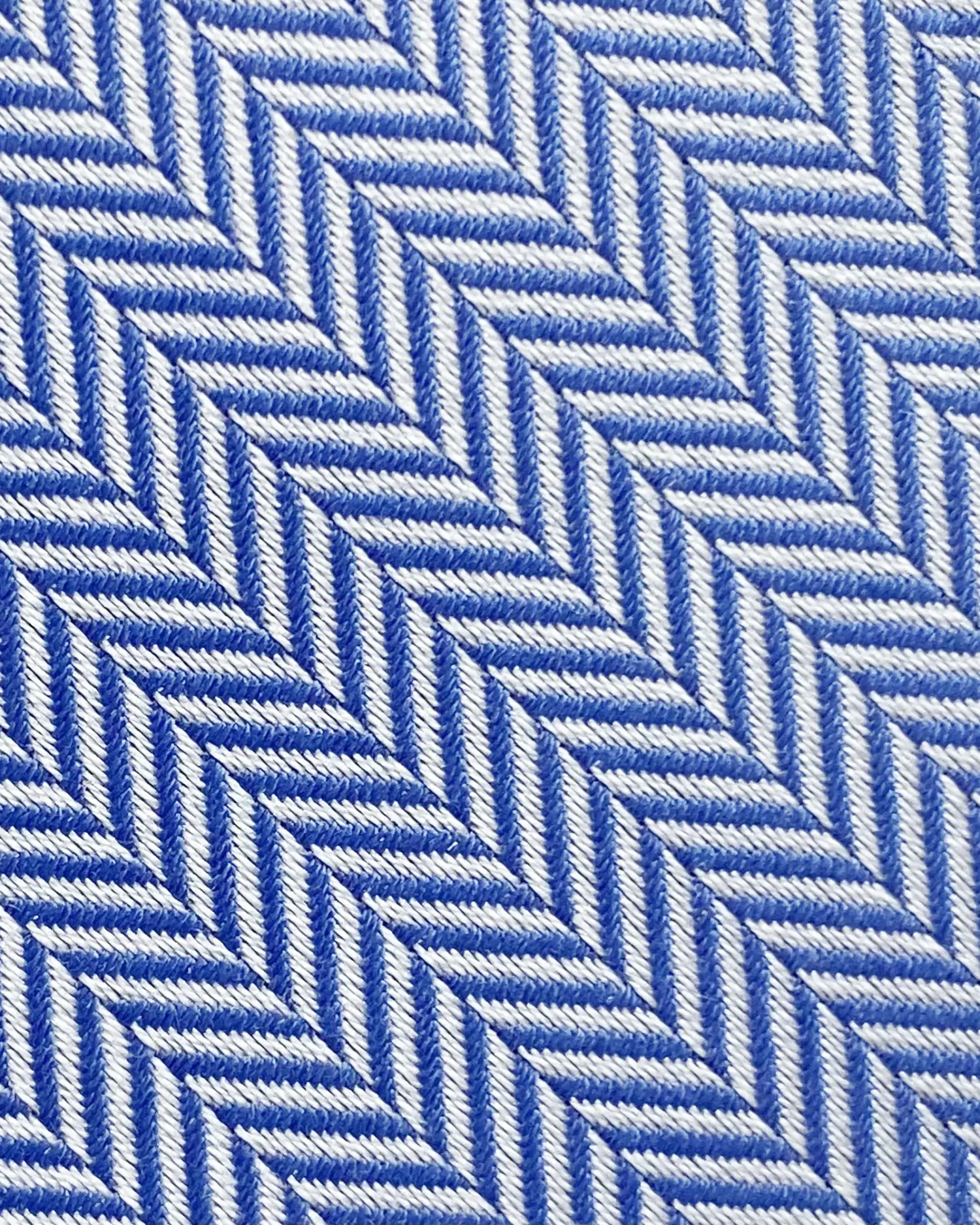 Blue and white herringbone fabric with diagonal geometric pattern, close-up view.