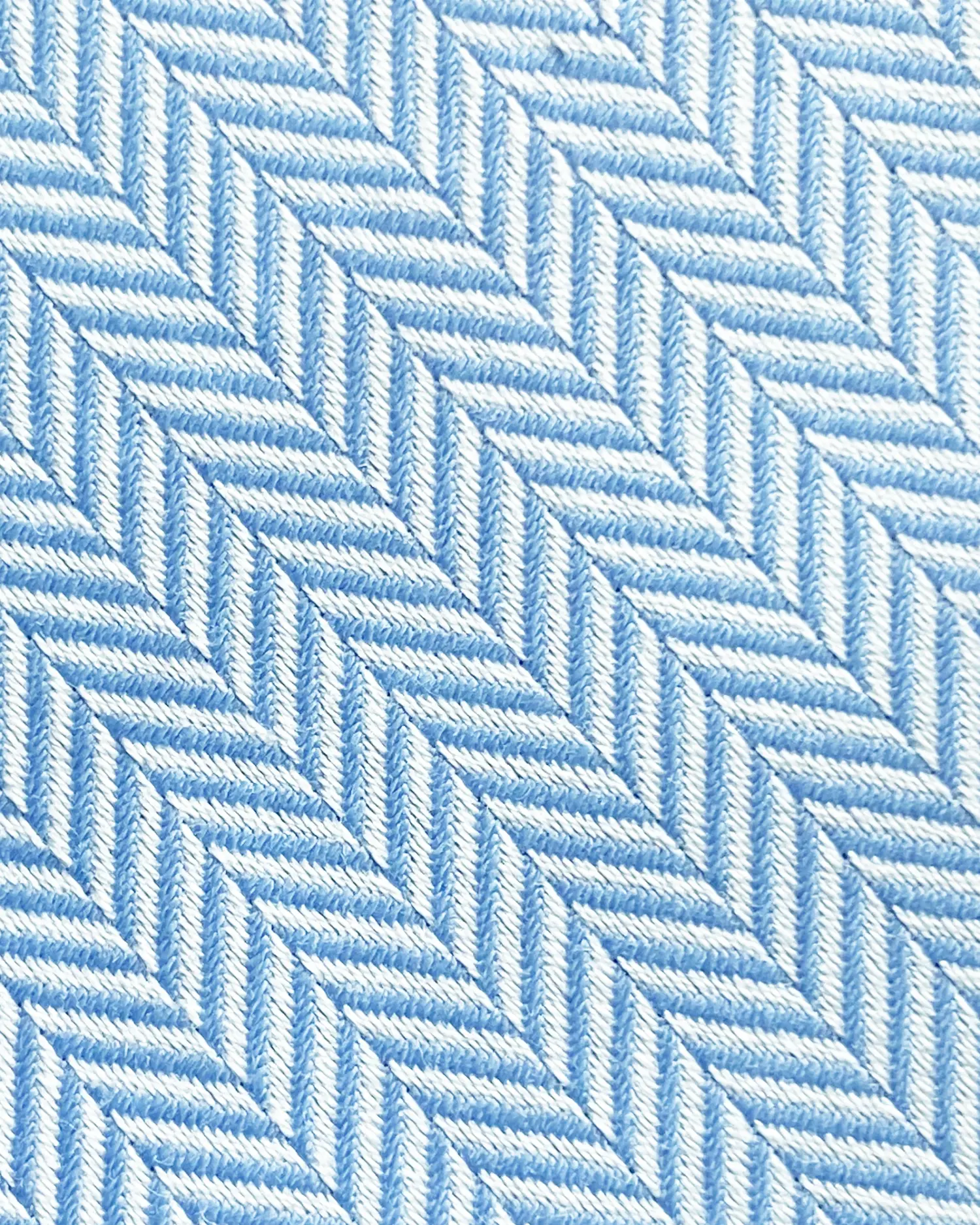 Close-up of blue and white herringbone fabric pattern with diagonal zigzag design.