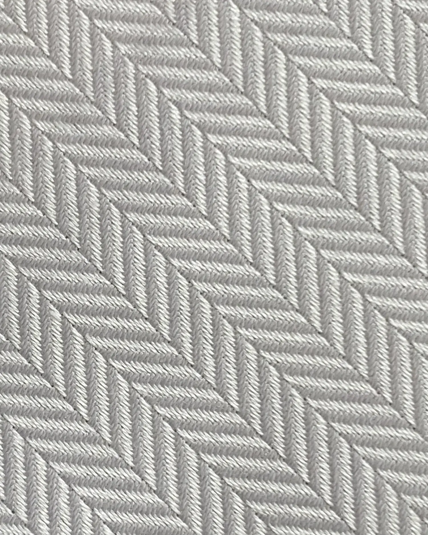 Close-up of a grey herringbone pattern fabric, showcasing detailed diagonal stitching.