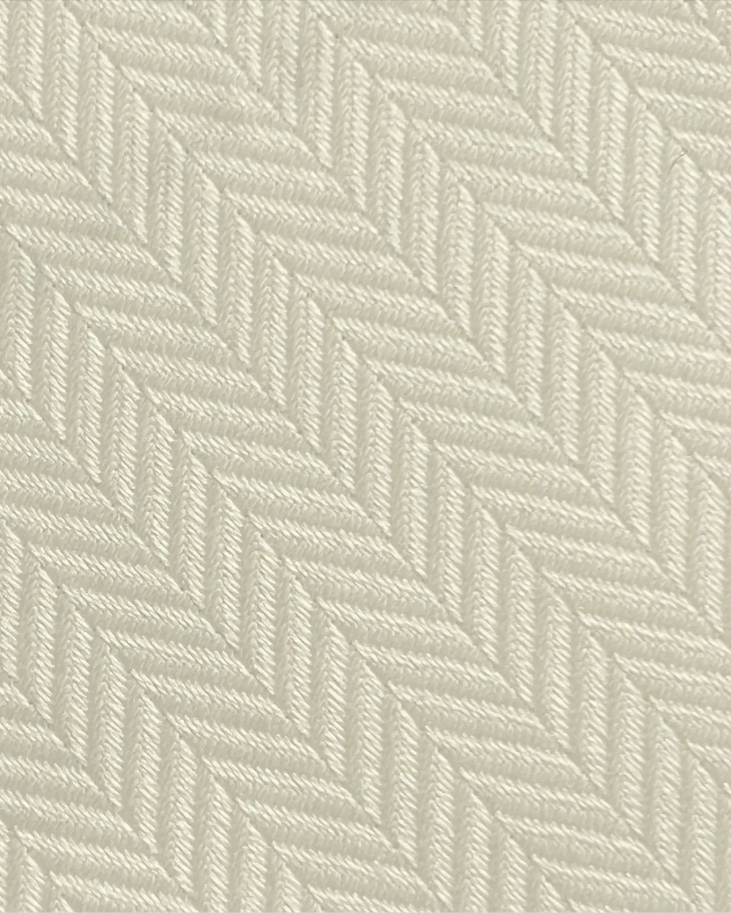 Close-up of a beige herringbone fabric texture, showcasing the intricate pattern and elegant design.