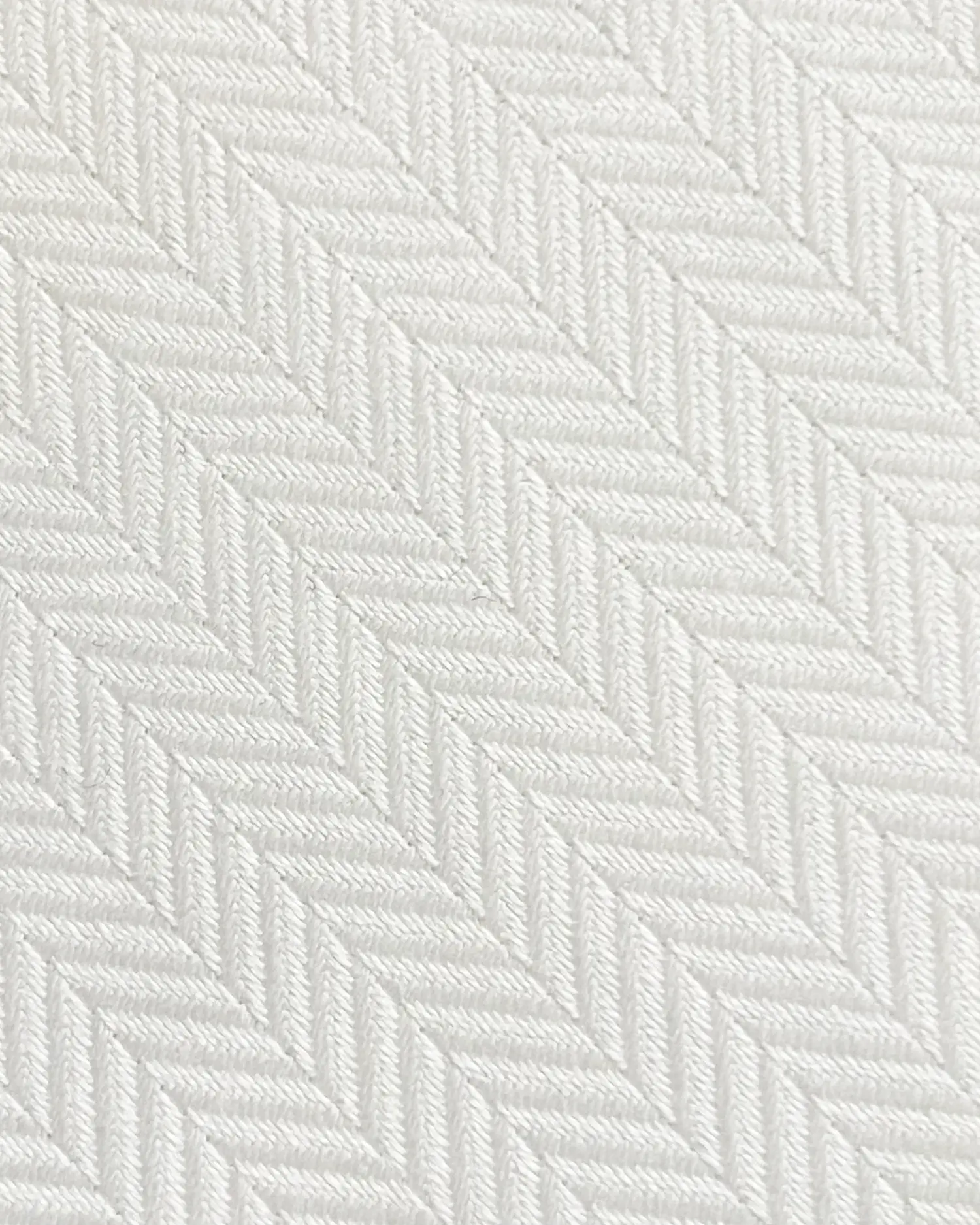 Close-up of a white herringbone fabric pattern, showcasing intricate texture and detailed diagonal weaving.