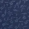 Close-up of denim fabric with blue floral and leaf patterns.