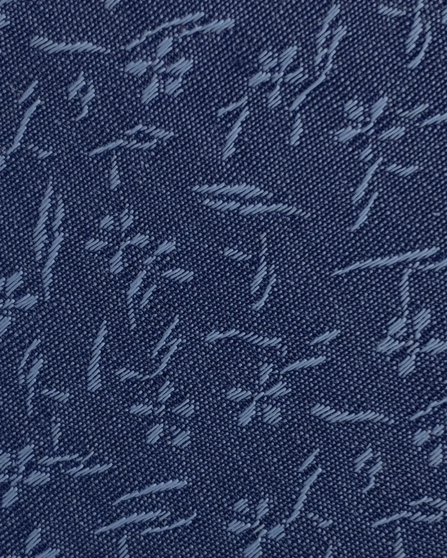 Close-up of denim fabric with blue floral and leaf patterns.