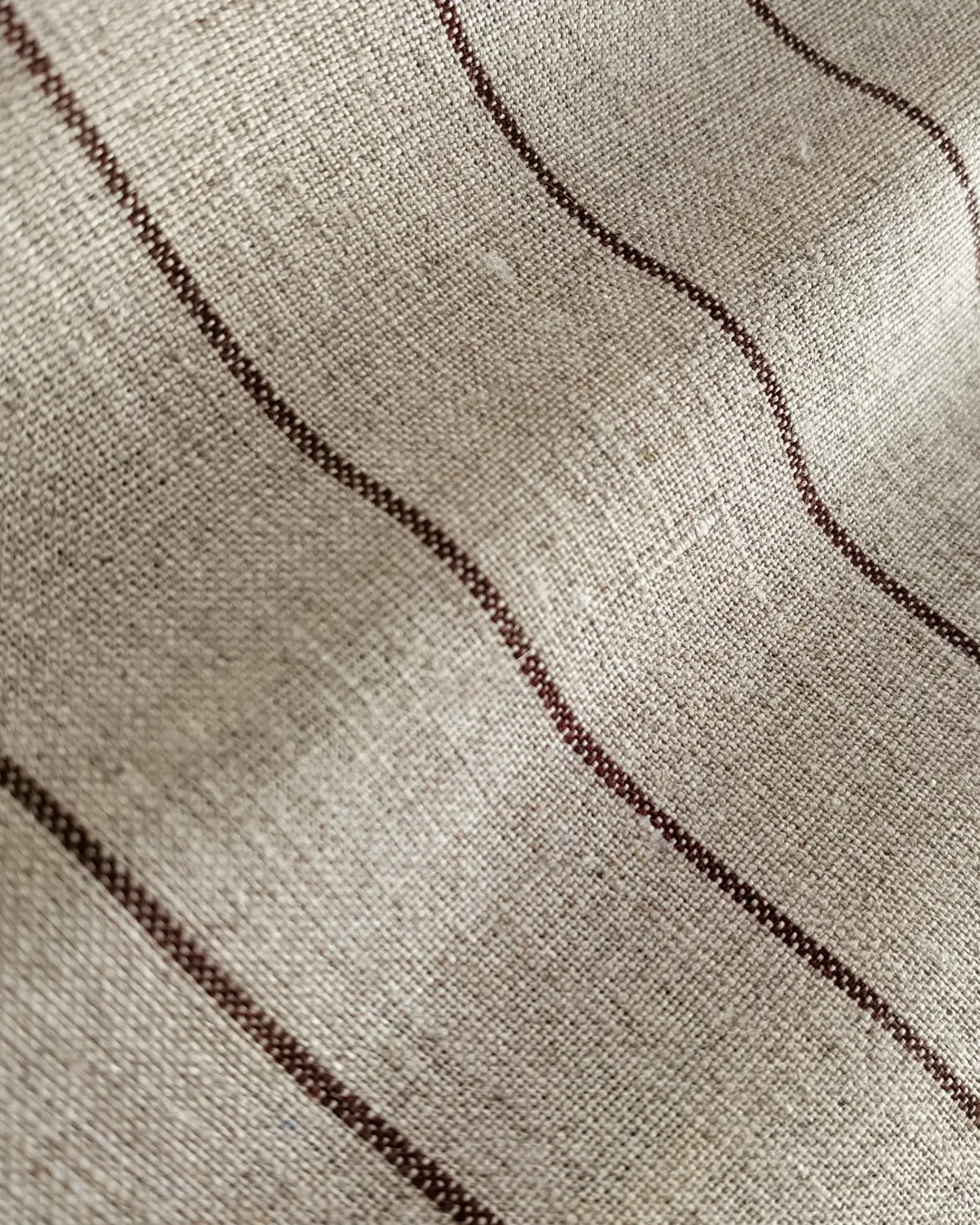 Close-up of beige fabric texture with wavy brown stripes.