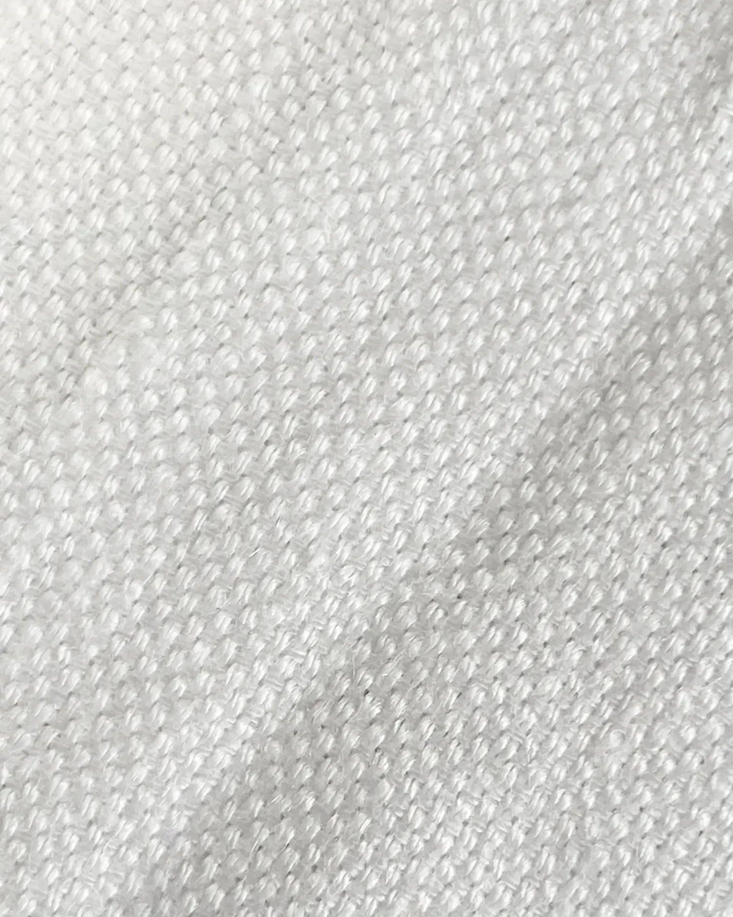 Close-up of textured white fabric with a woven pattern, showcasing textile detail and quality.