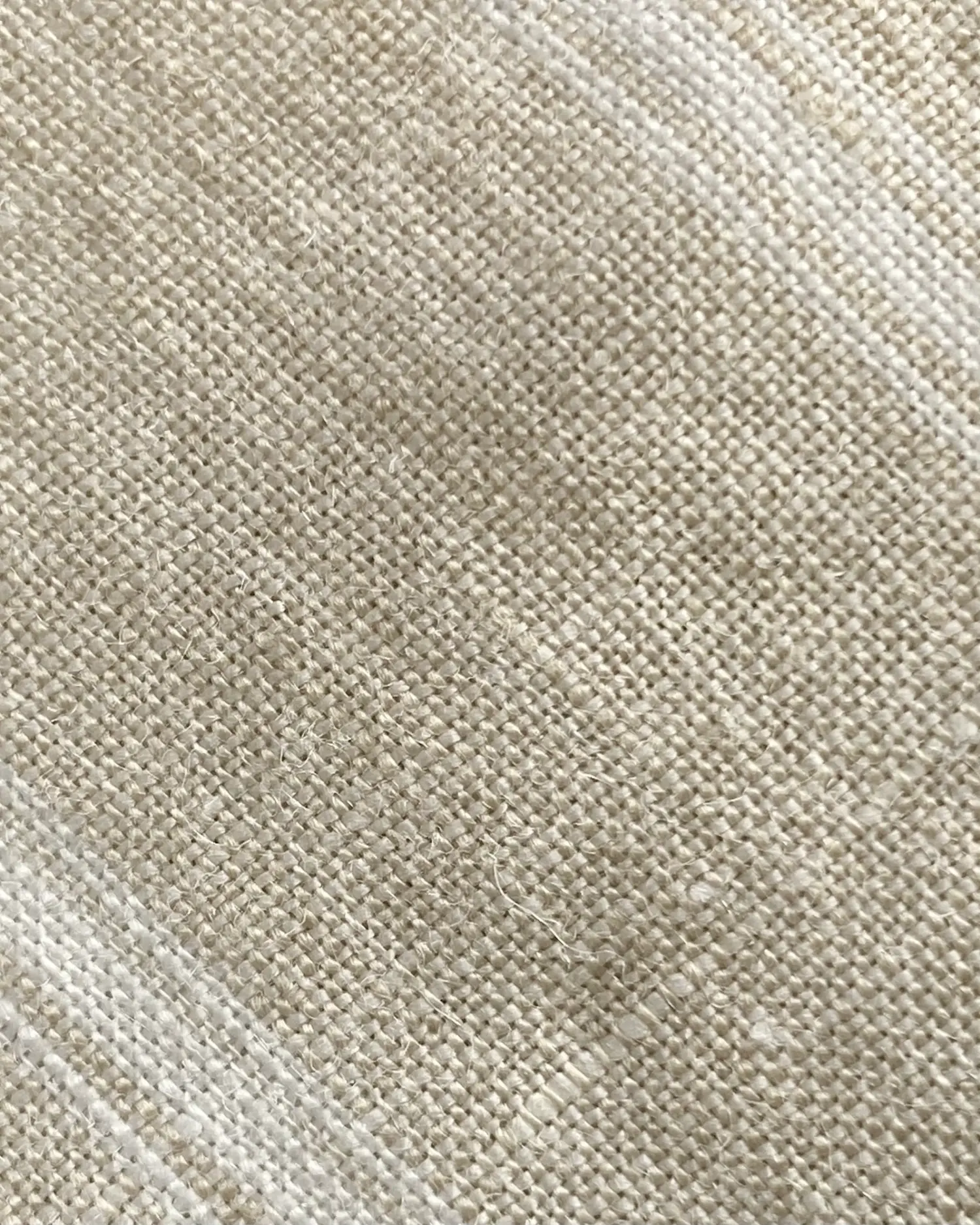 Close-up of beige burlap fabric texture, showing woven fibers and natural pattern.