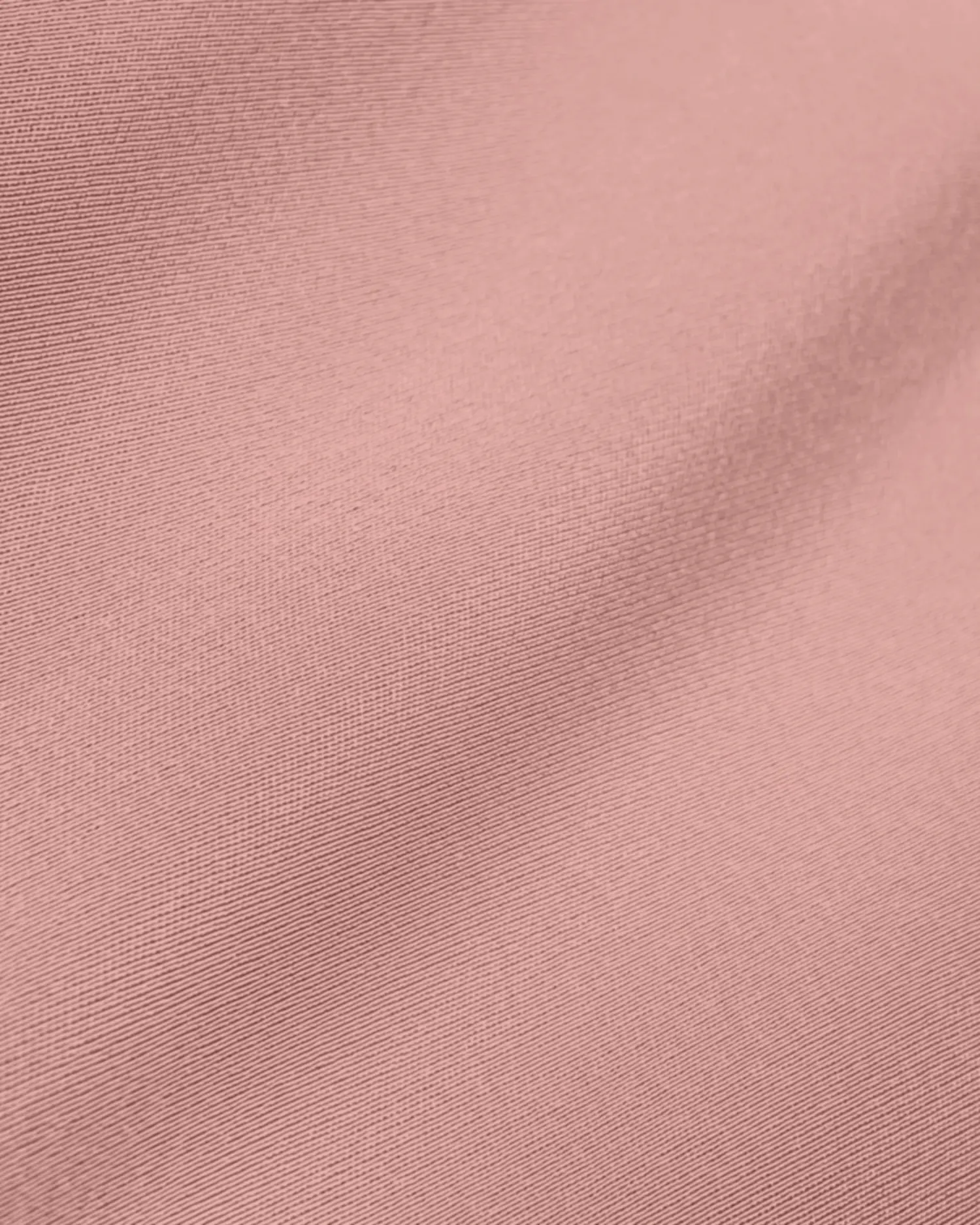 Close-up of smooth pink fabric texture with subtle shine and soft folds.