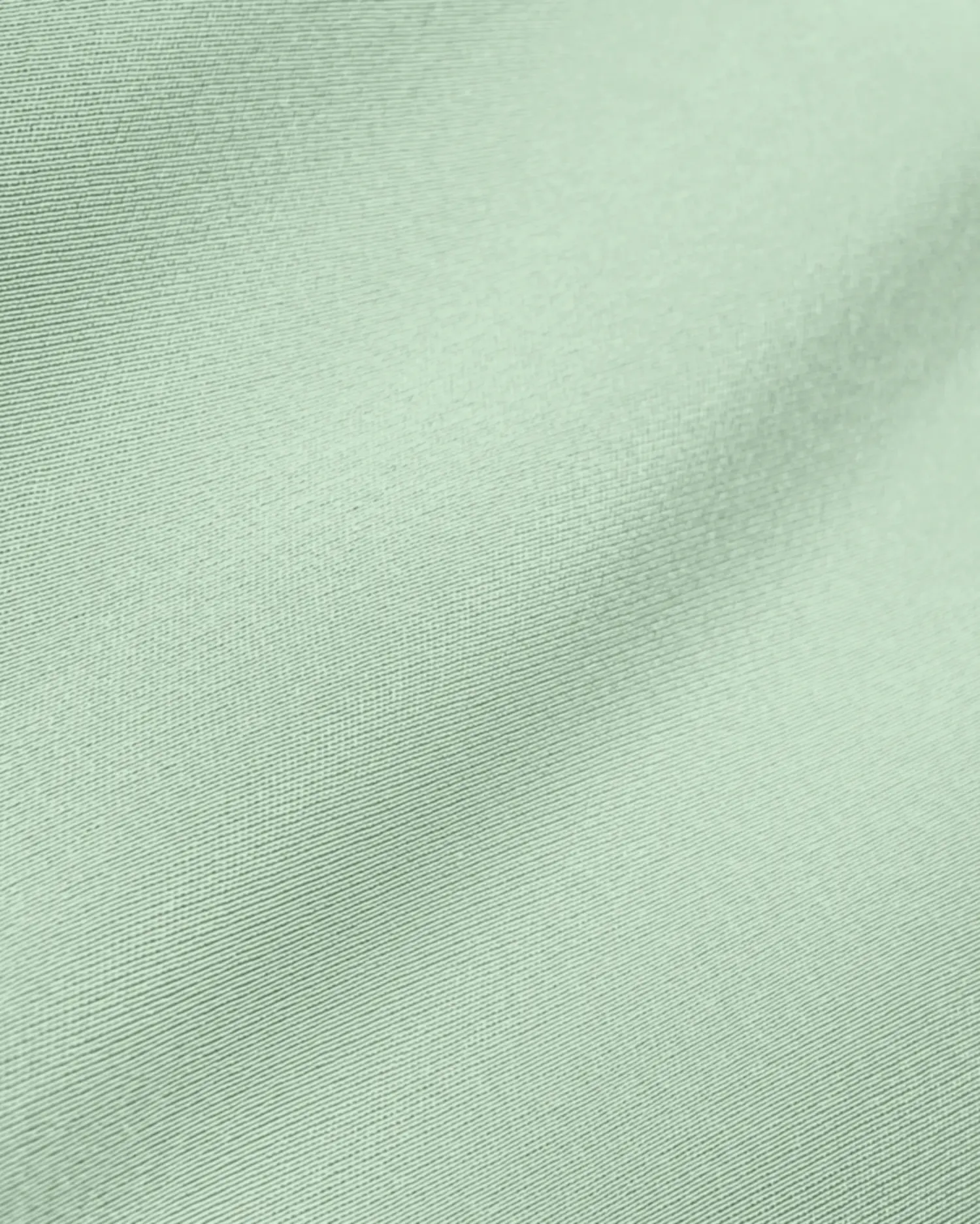 Close-up of light green fabric texture with subtle sheen and soft folds.