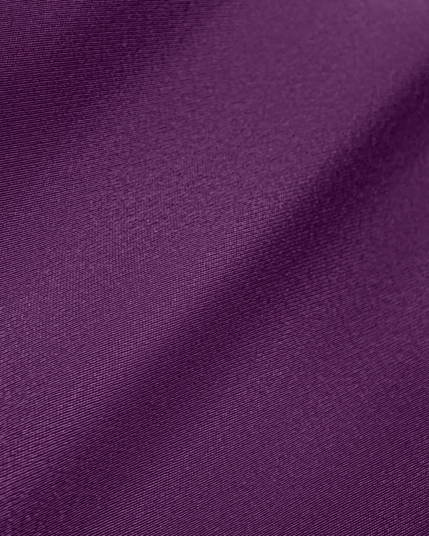Close-up of textured purple fabric forming soft waves, showcasing rich color and smooth texture. Ideal for fashion design.
