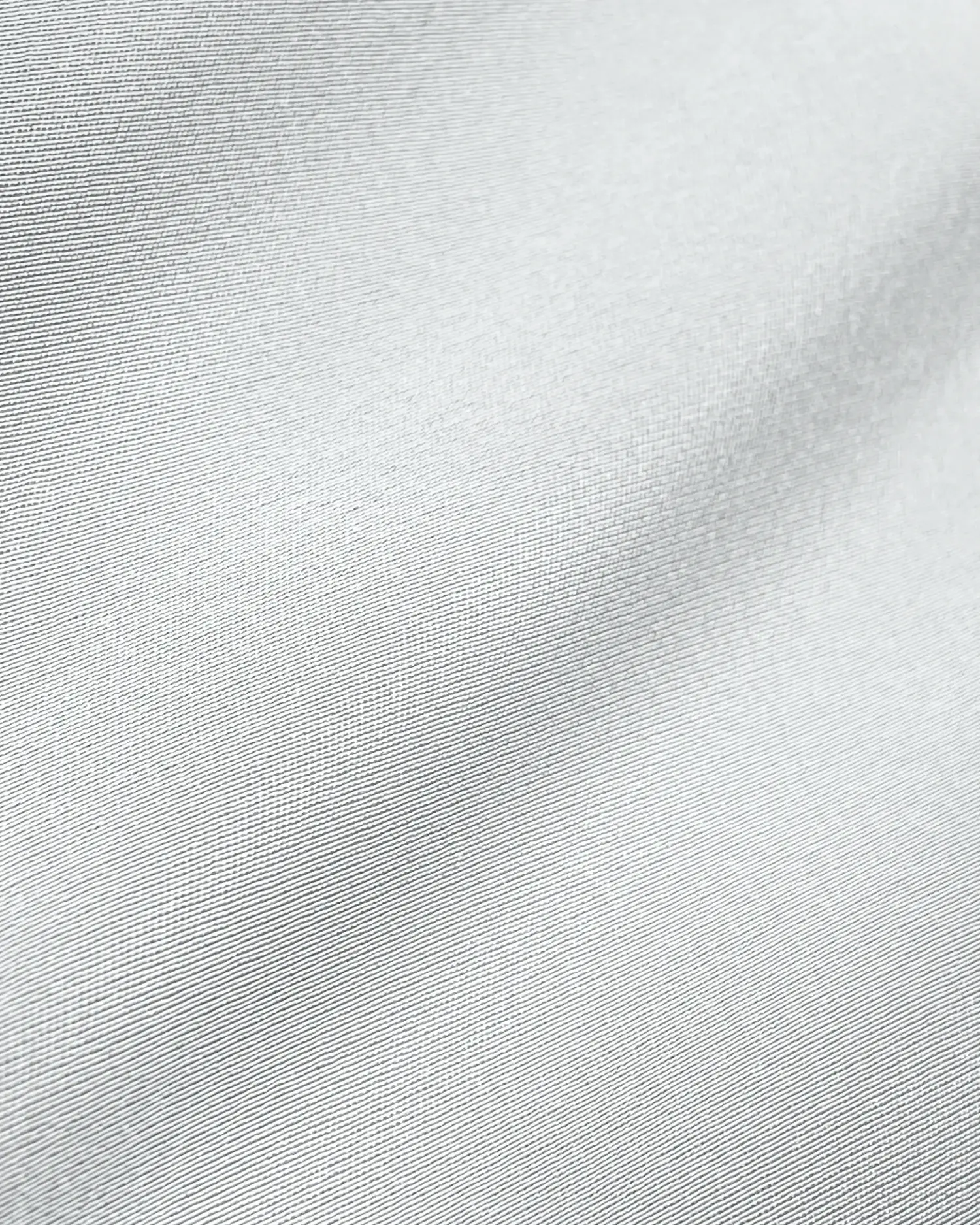 Close-up of a smooth, white fabric texture with gentle folds and a subtle sheen.