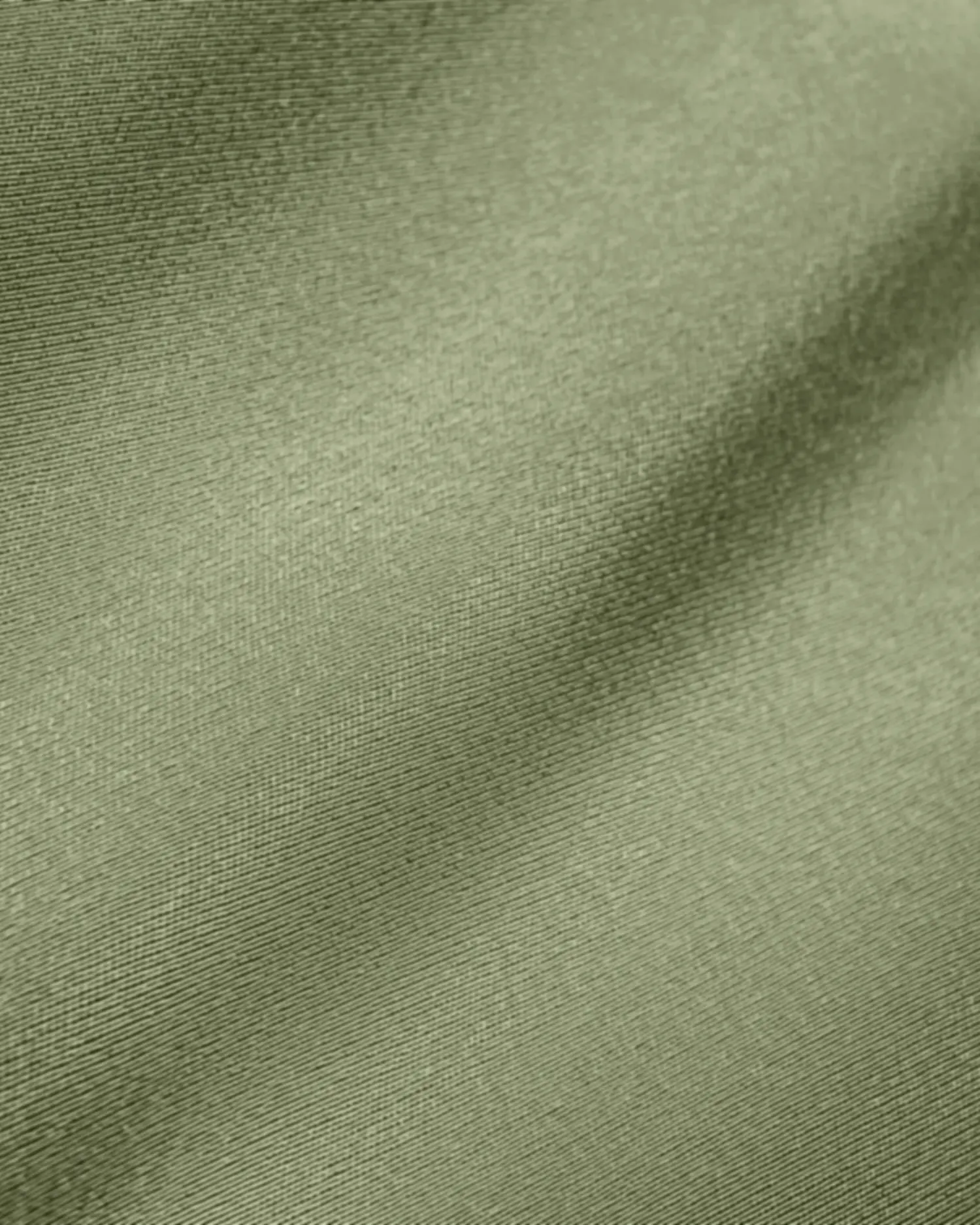 Smooth green fabric with soft, flowing texture, ideal for backgrounds or textile design concepts.