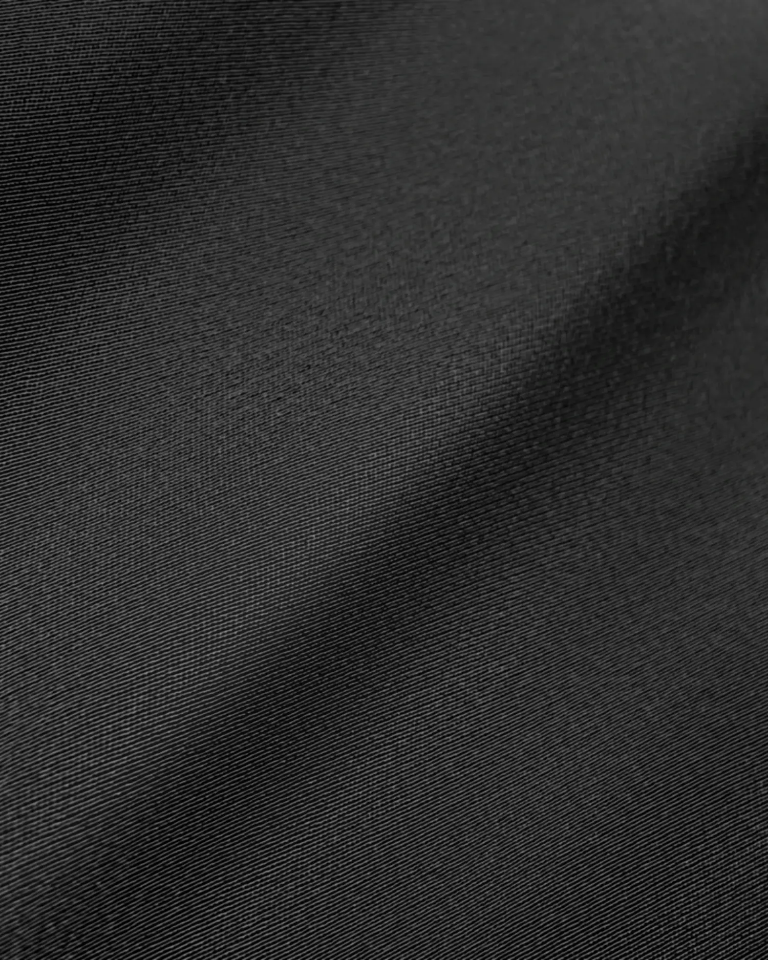 Close-up of smooth, dark gray fabric texture with fine details and subtle lighting.