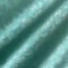 Teal fabric with embossed butterfly and flower patterns, creating a textured and elegant appearance.