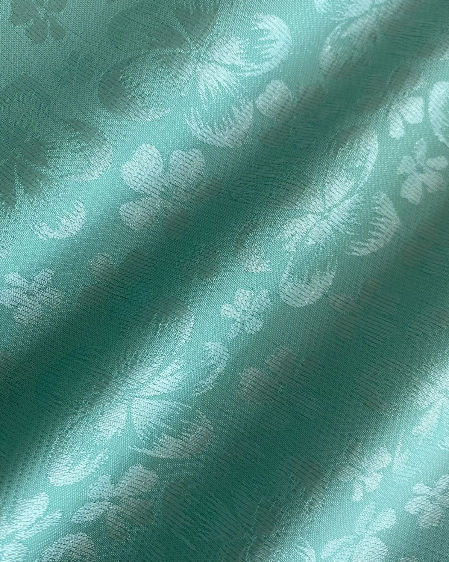 Teal fabric with embossed butterfly and flower patterns, creating a textured and elegant appearance.