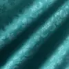Teal fabric with a delicate floral texture, highlighting elegant embossed patterns in the sunlight.