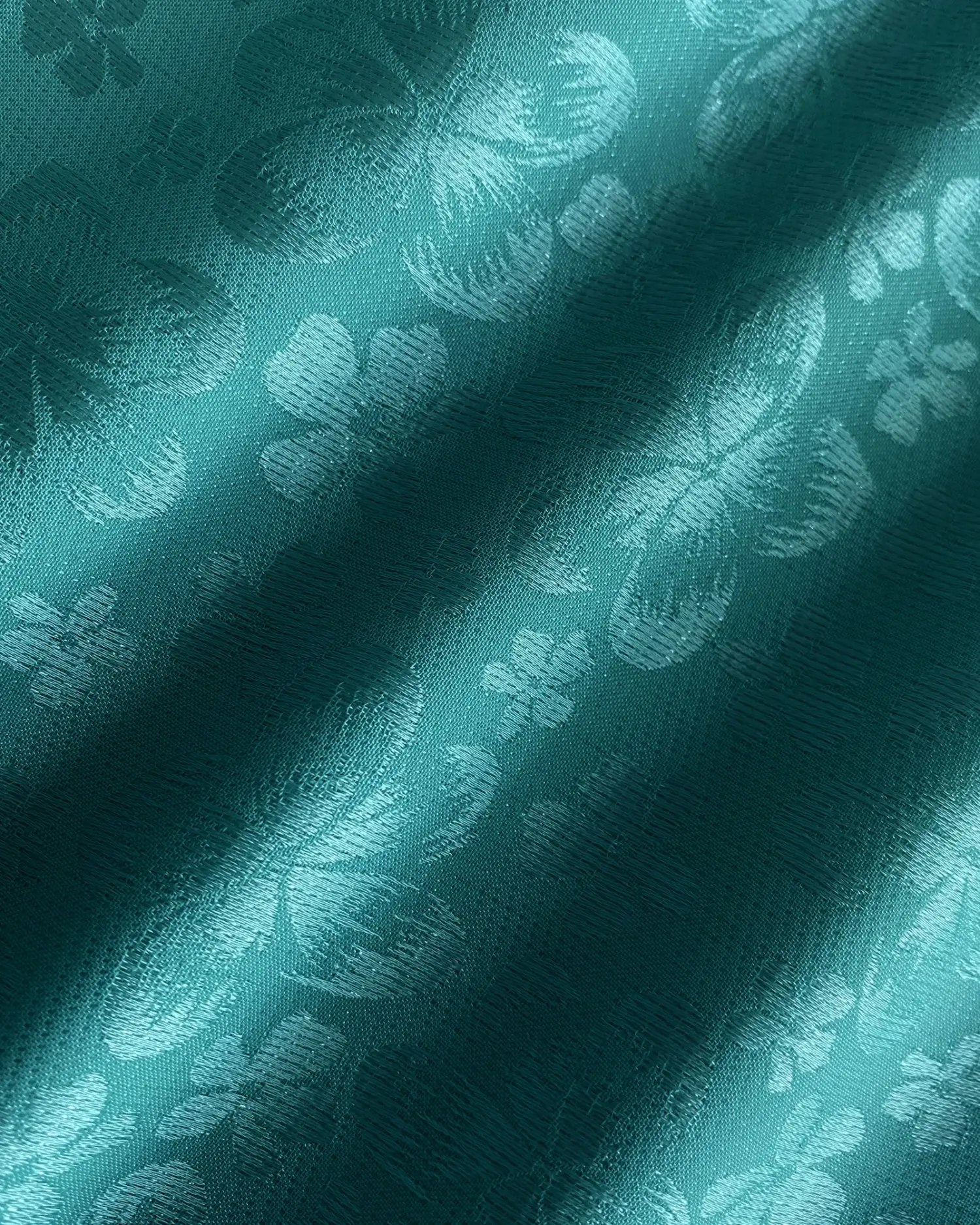 Teal fabric with a delicate floral texture, highlighting elegant embossed patterns in the sunlight.