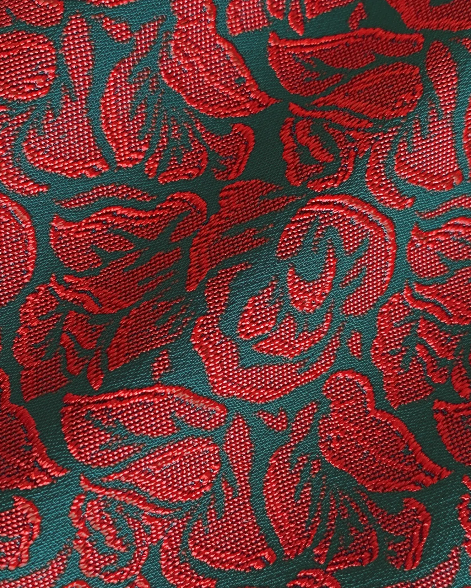 Rich red floral jacquard pattern on textured fabric with a green background.