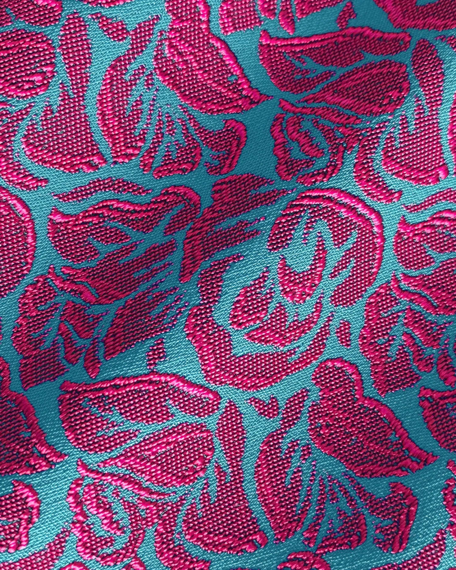 Teal fabric with vibrant pink floral embroidery pattern, showcasing intricate design details and rich texture.