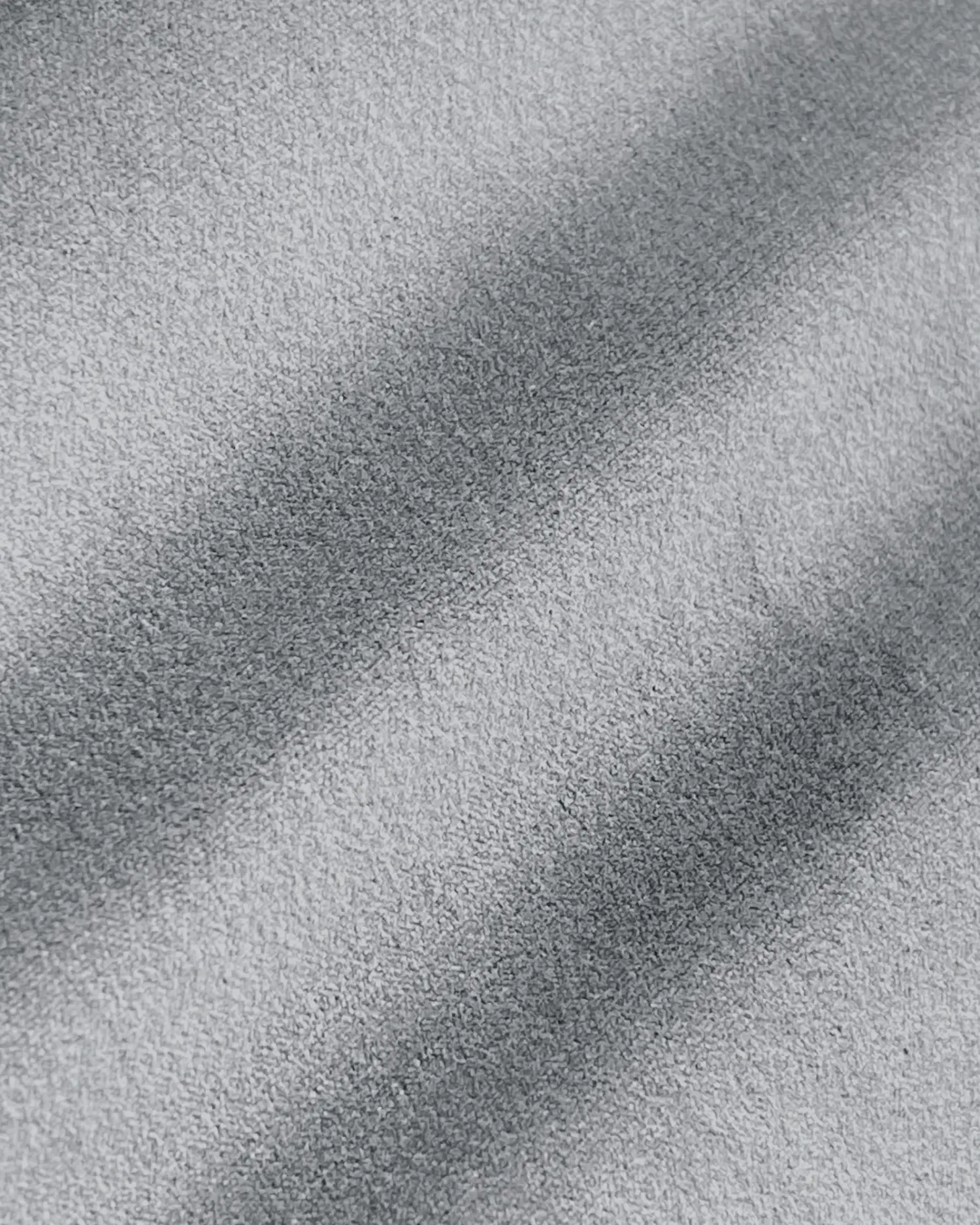 Close-up of a textured surface with shadowy diagonal lines, creating an abstract pattern. Black and white color scheme.