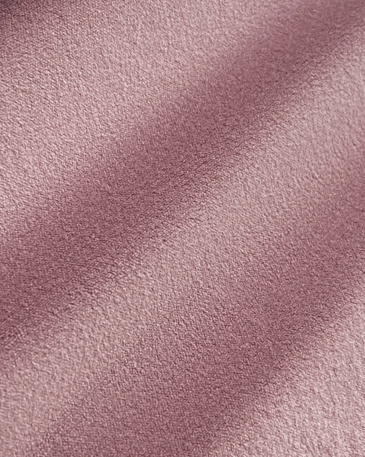 Close-up of soft pink suede fabric texture with subtle shadowing.