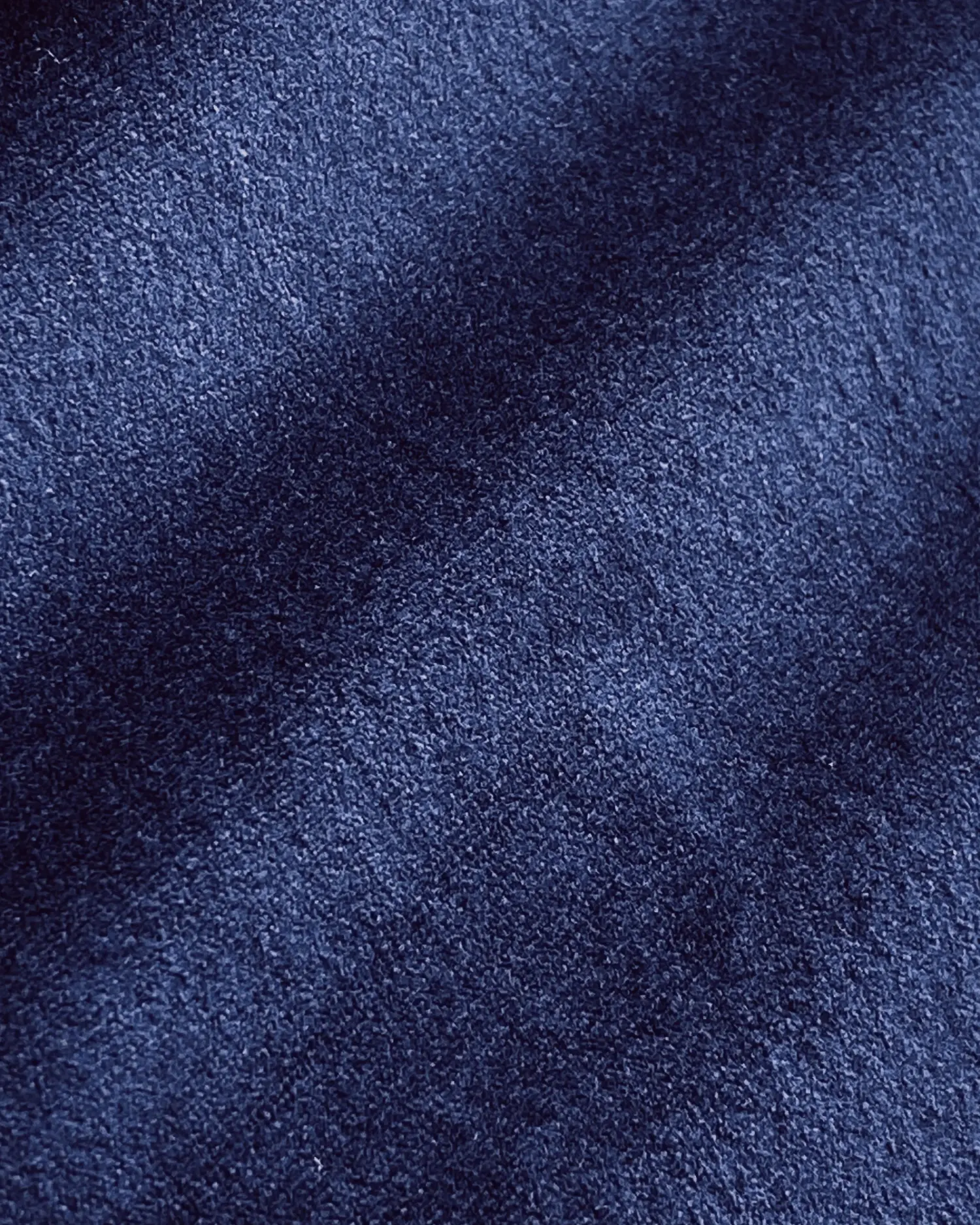Close-up of soft, textured dark blue fabric with subtle shadows, conveying luxury and comfort.