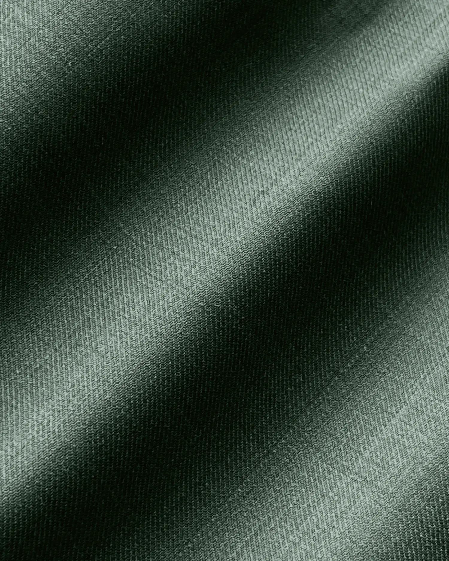 Close-up of green textured fabric with diagonal shadows creating a striped pattern.
