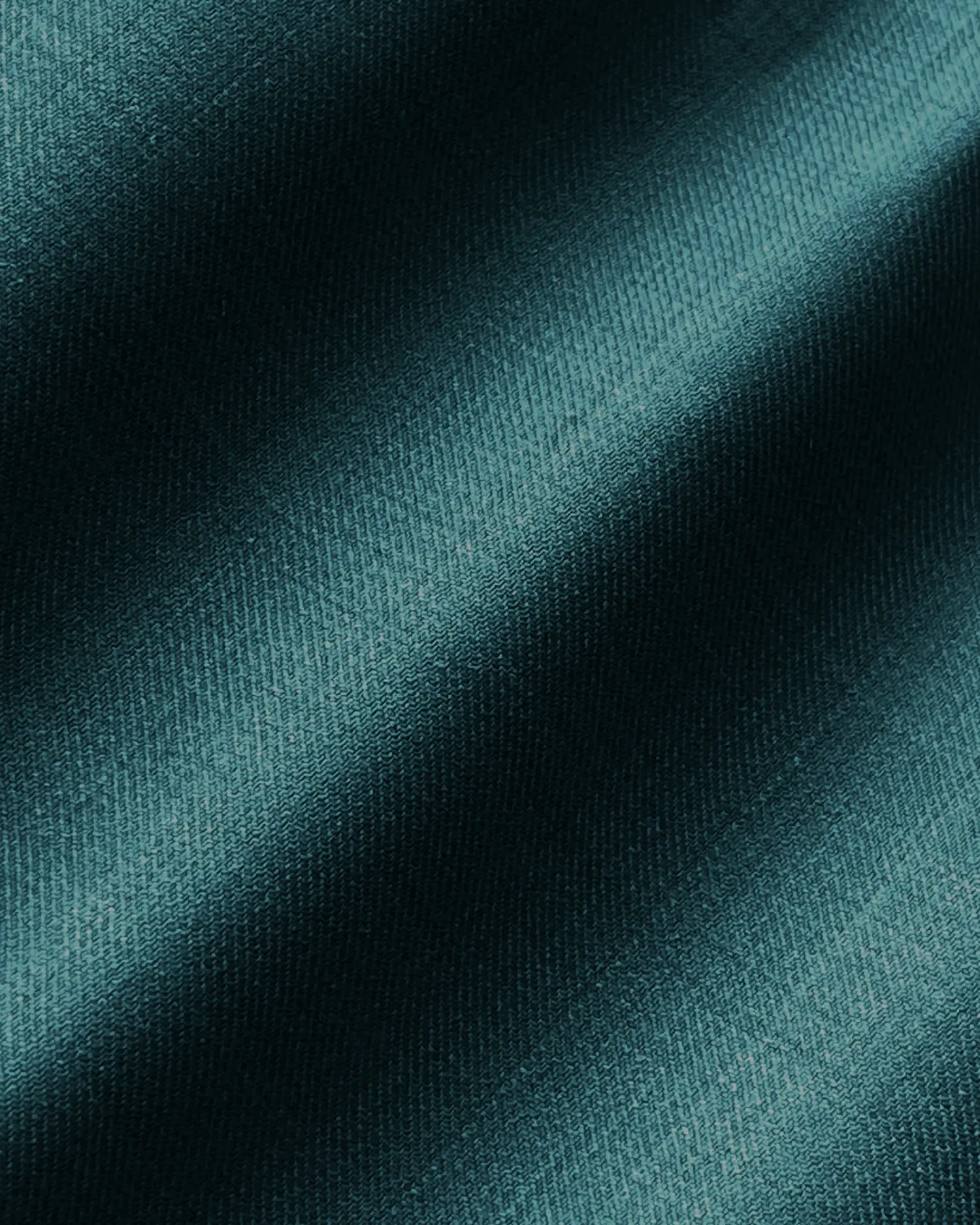 Close-up of textured dark teal fabric with diagonal shadows.