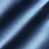 Close-up of textured blue denim fabric with diagonal shadows, highlighting woven details and rich color.