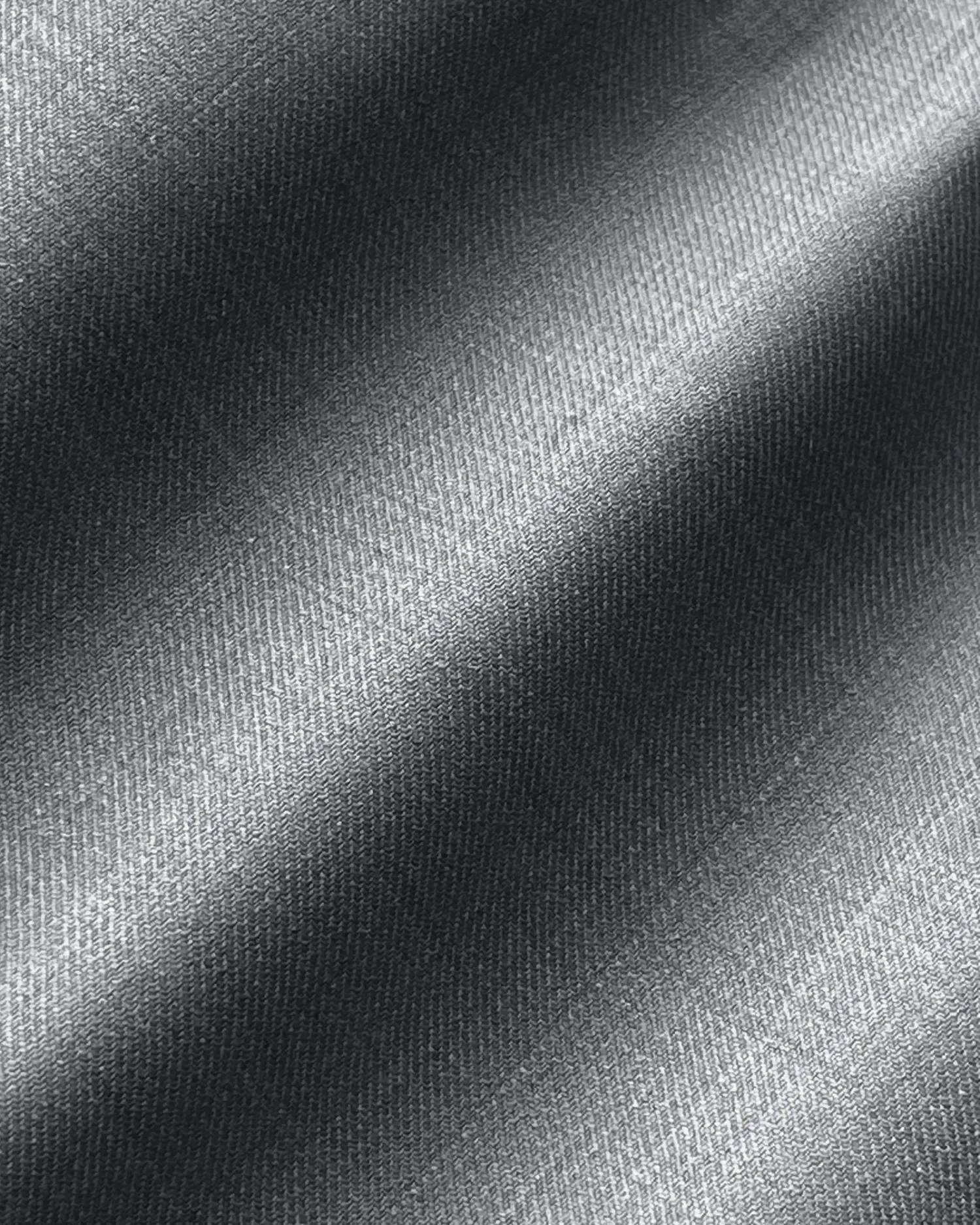 Close-up of textured gray fabric with diagonal light and shadow patterns, showing fine weave detail.