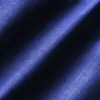Close-up of textured blue fabric with diagonal light and shadow pattern.