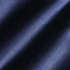 Close-up of textured blue denim fabric with diagonal shadows and a soft sheen.