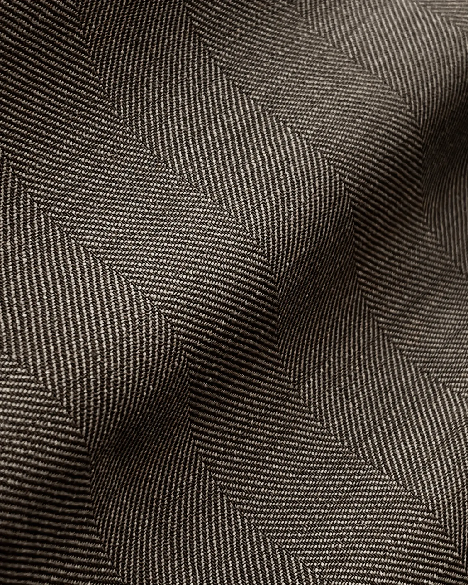Close-up of textured herringbone fabric with wavy folds, showcasing intricate weave patterns and depth.