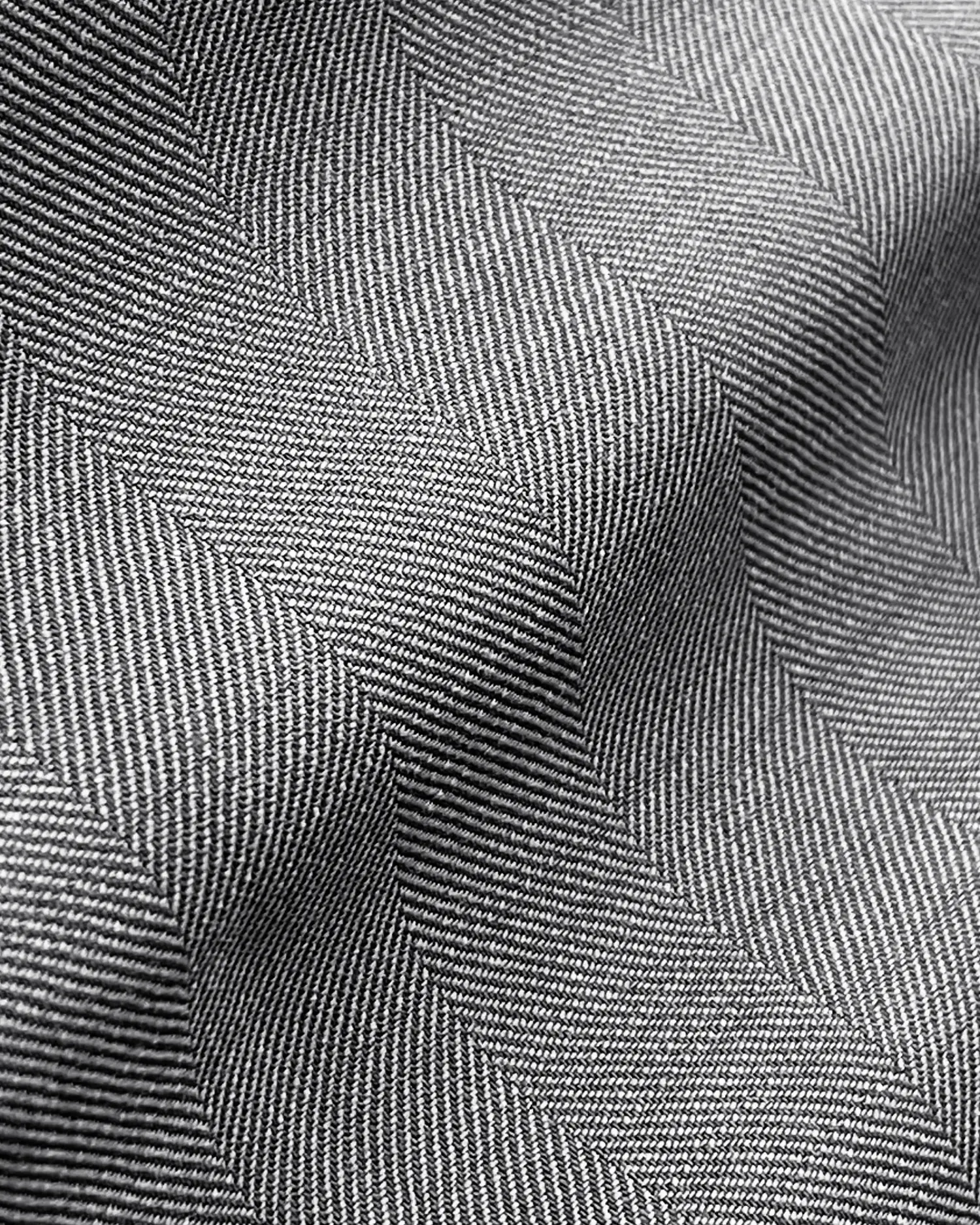 Close-up of gray herringbone fabric texture with wavy folds, showcasing detailed pattern and texture.