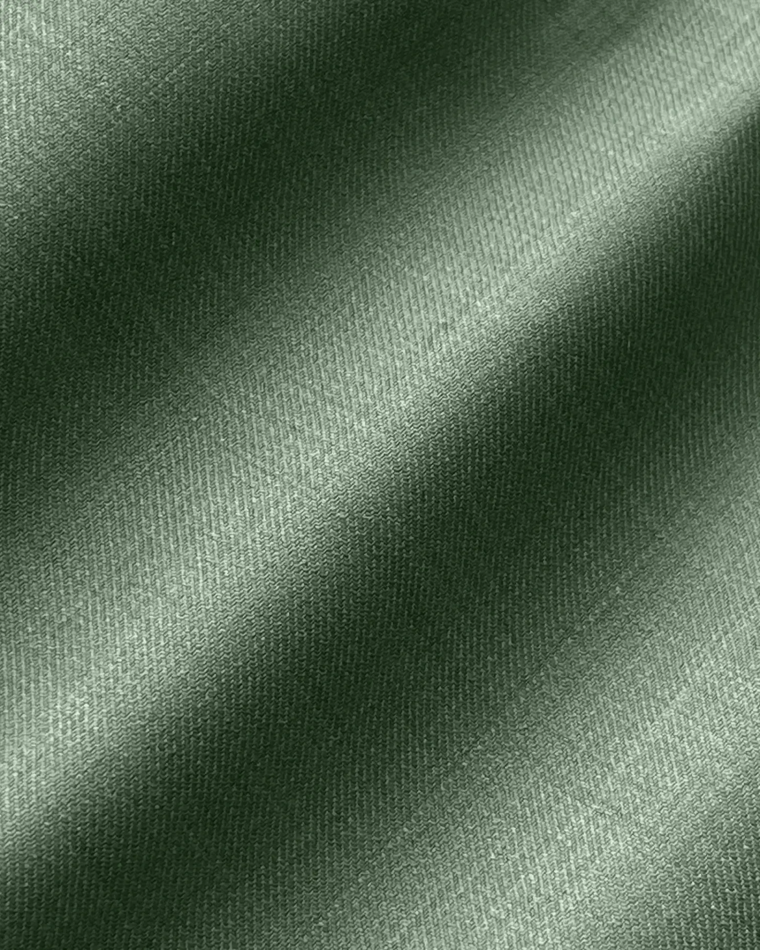 Close-up of green fabric texture with diagonal shadows, showcasing smooth and detailed textile pattern.