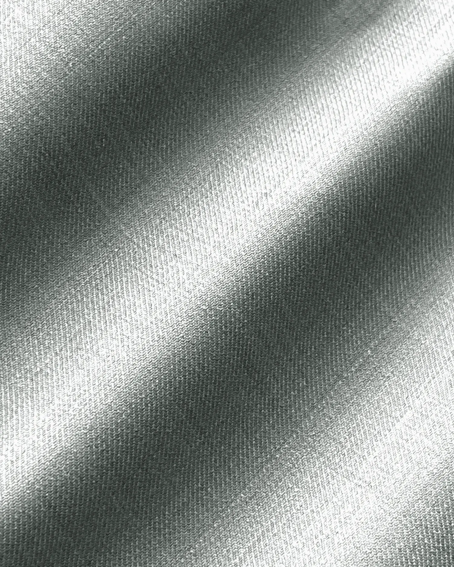 Close-up of smooth, silver metallic fabric with diagonal lighting highlights.
