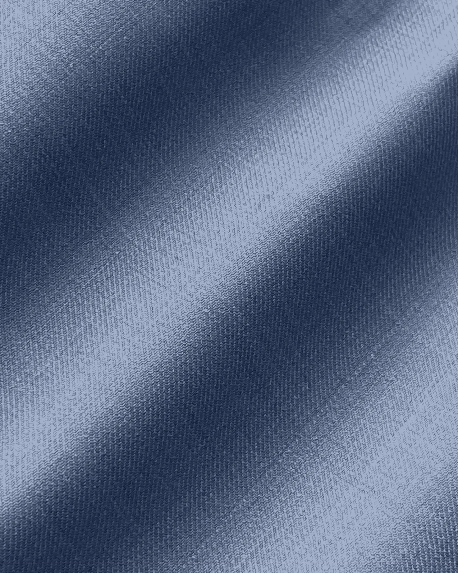 Close-up of blue denim fabric texture with diagonal weave pattern, showcasing clothing material details.