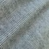 Close-up of gray plaid fabric with a textured pattern, ideal for clothing or upholstery design.