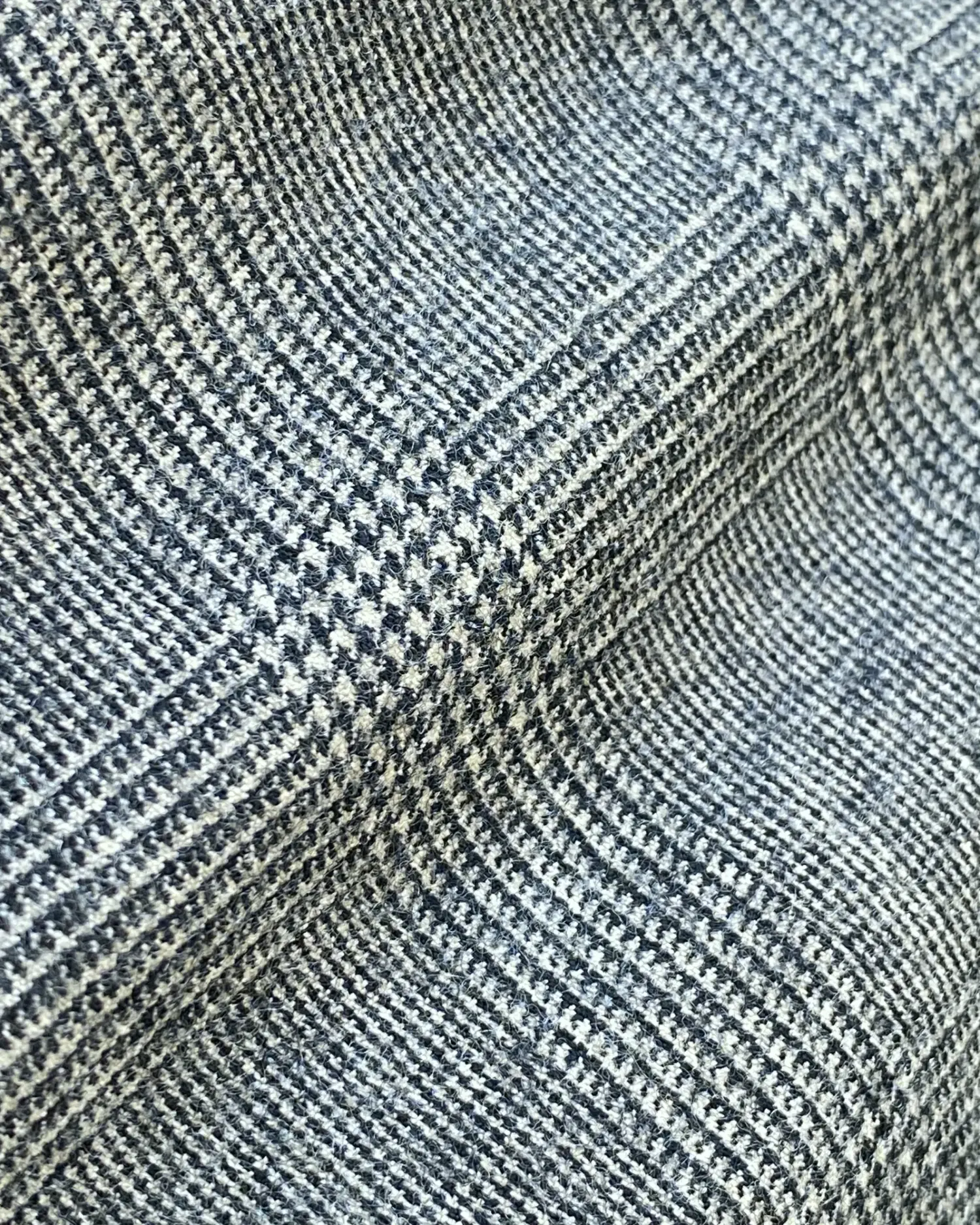 Close-up of gray plaid fabric with a textured pattern, ideal for clothing or upholstery design.