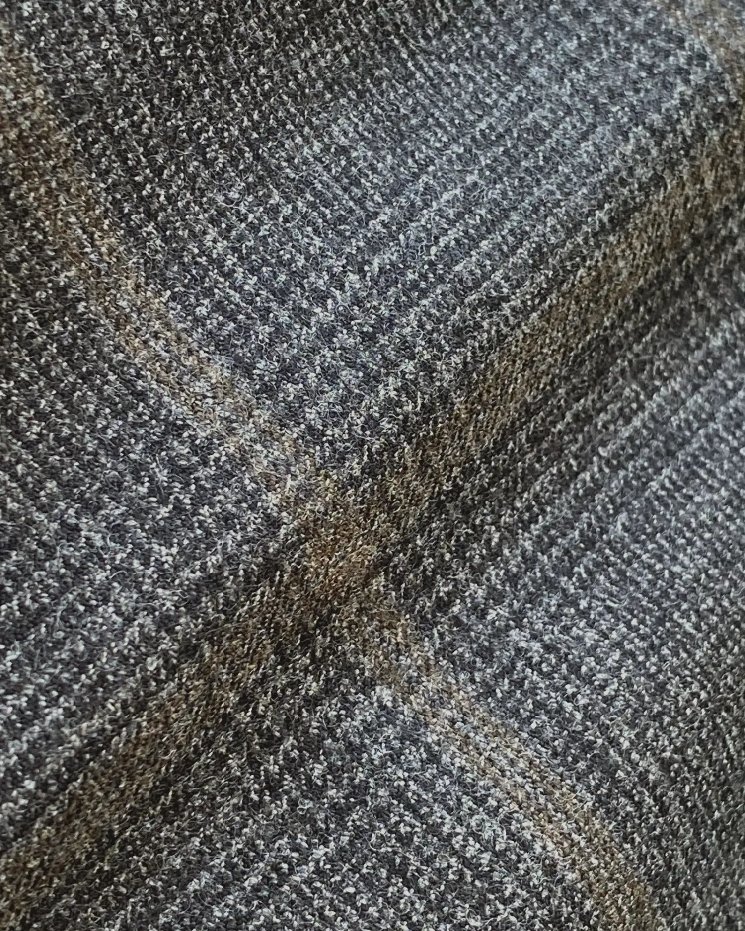 Close-up of a textured gray and brown fabric with a subtle plaid pattern, perfect for cozy textiles and stylish decor.