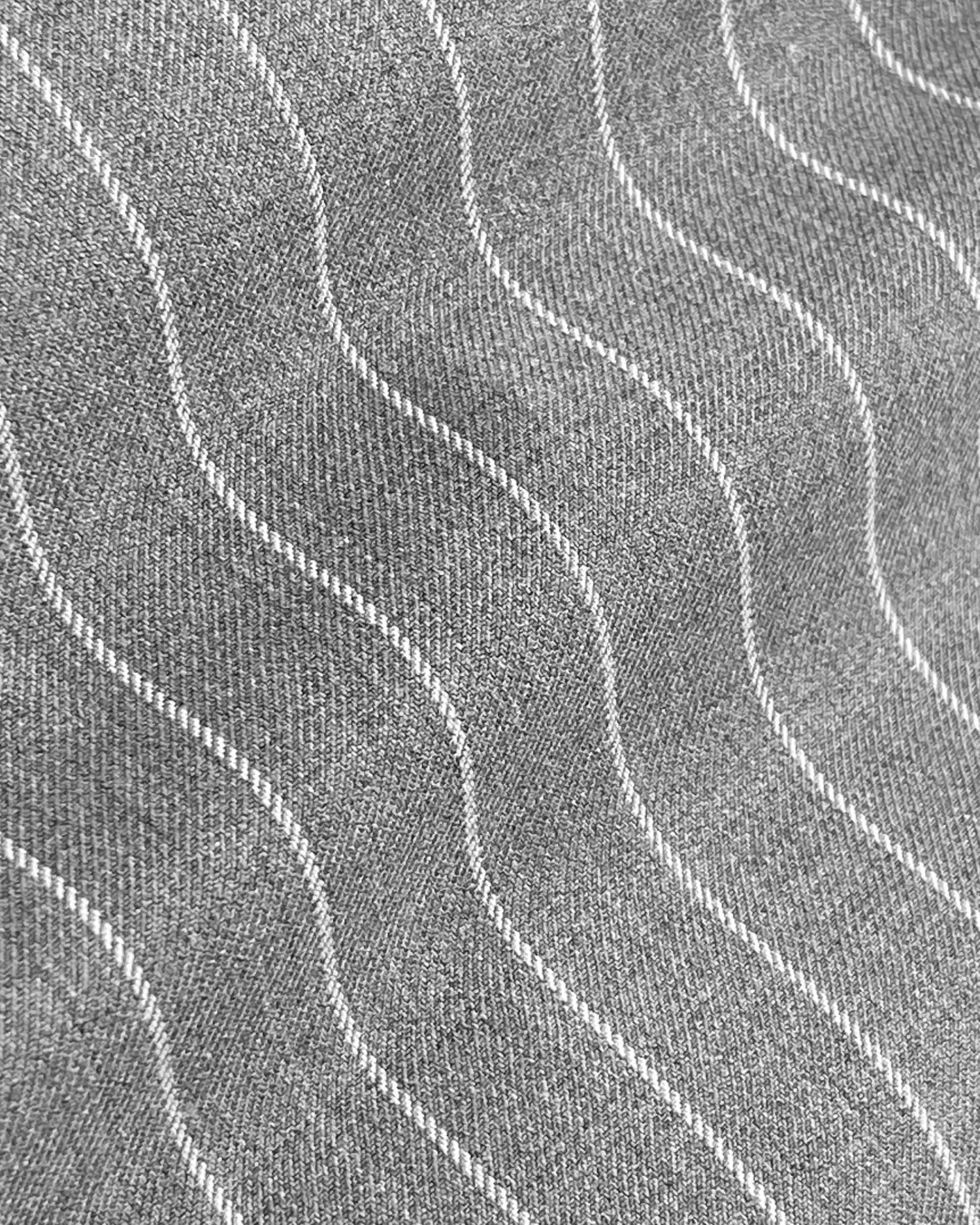 Close-up of gray fabric with wavy white pinstripes pattern creating a textured surface.