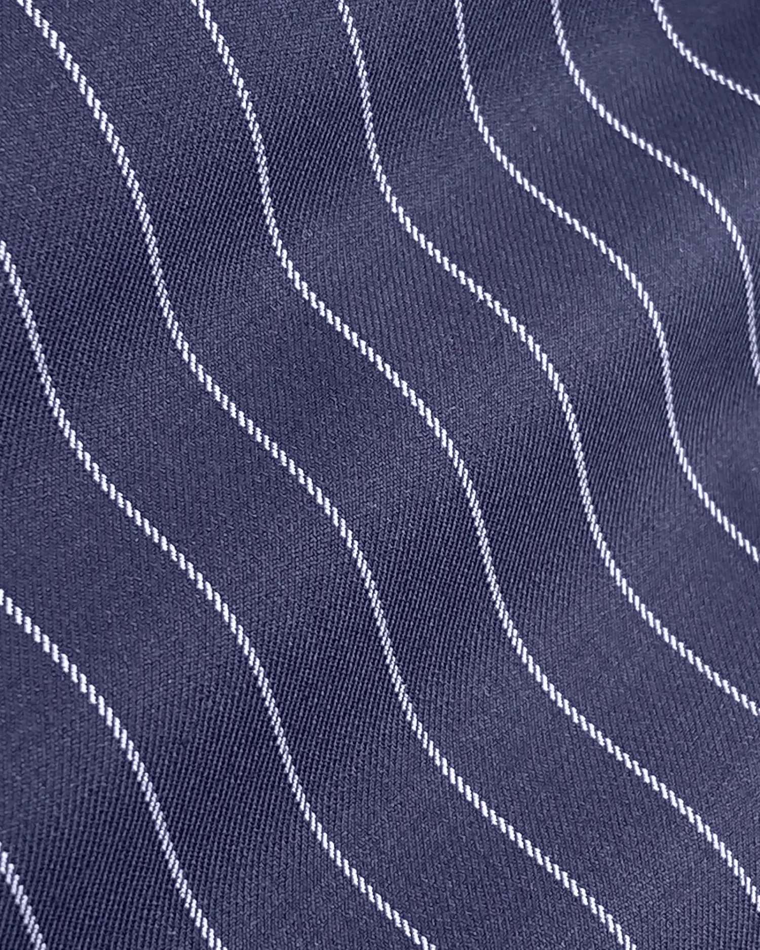 Close-up of navy fabric with wavy white pinstripes pattern, creating a textured and stylish textile background.