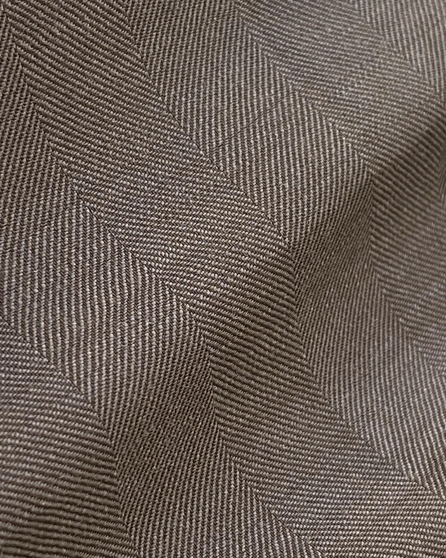 Brown herringbone fabric texture with fine zigzag pattern, showcasing textile detail and design.