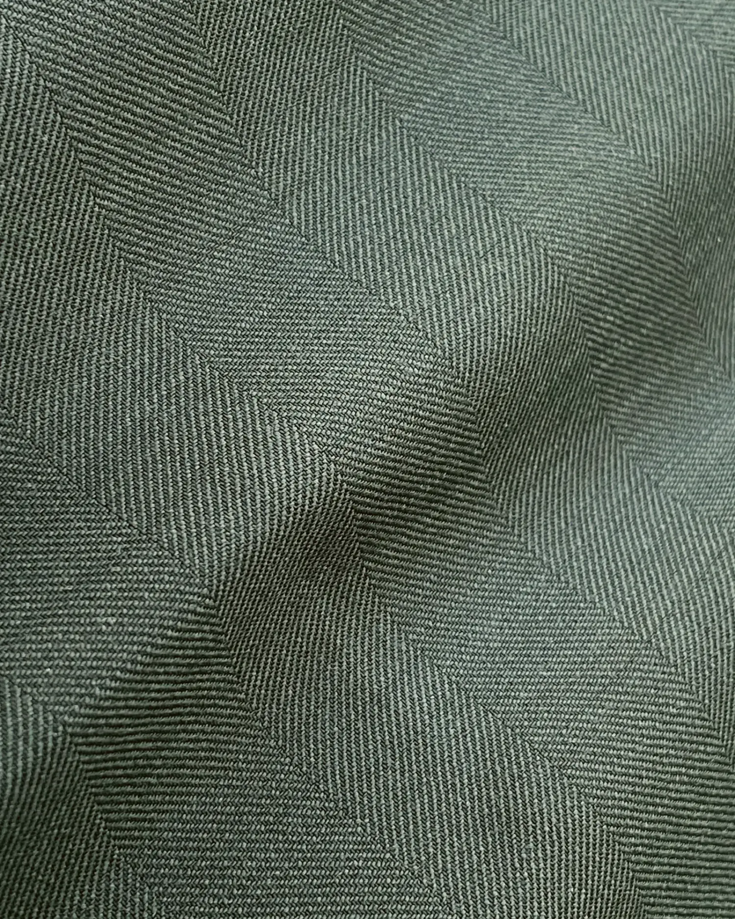 Close-up of gray herringbone fabric texture, showcasing the detailed zigzag pattern and fine textile weave.