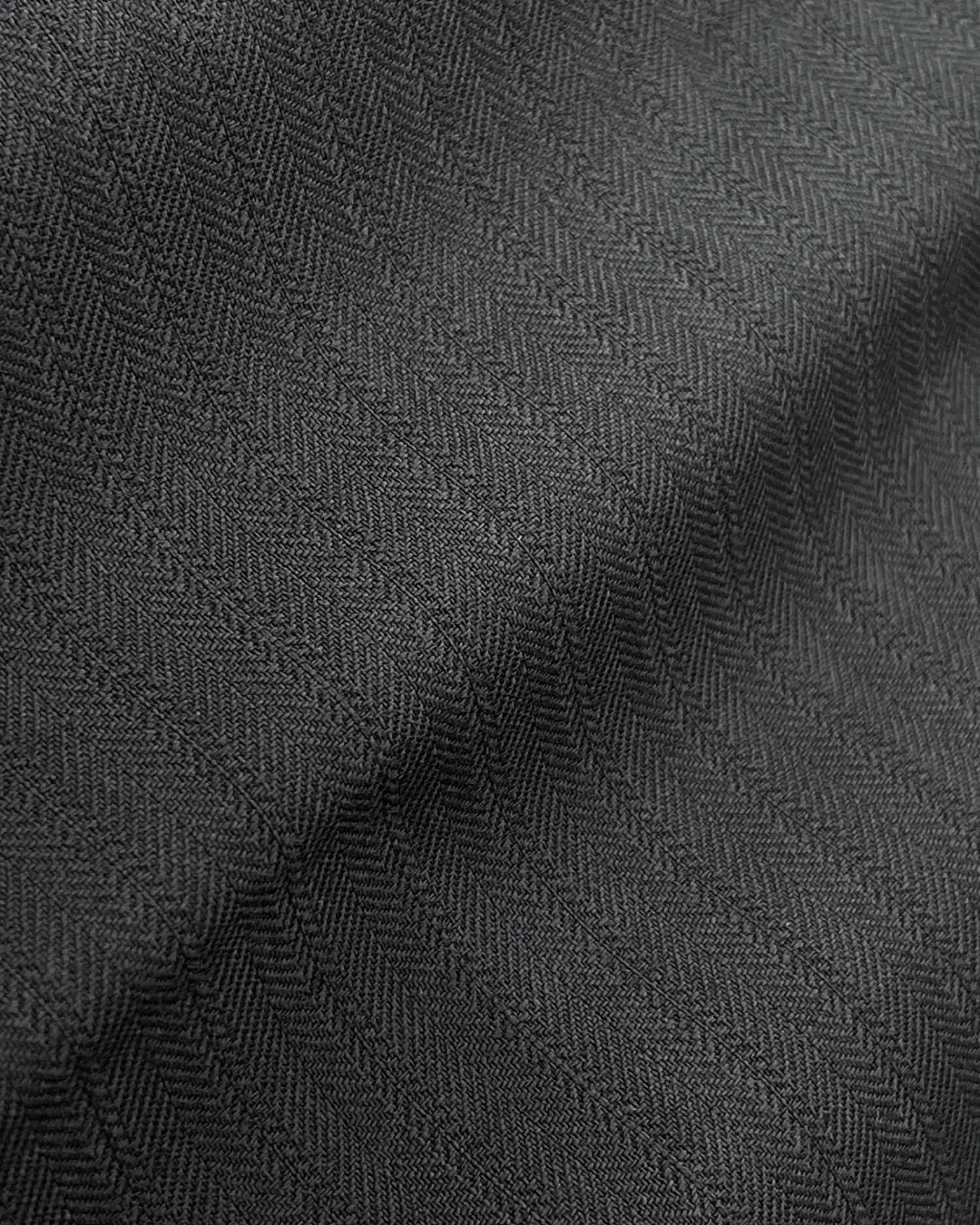 Close-up of black fabric with a herringbone texture, showcasing detailed woven pattern.